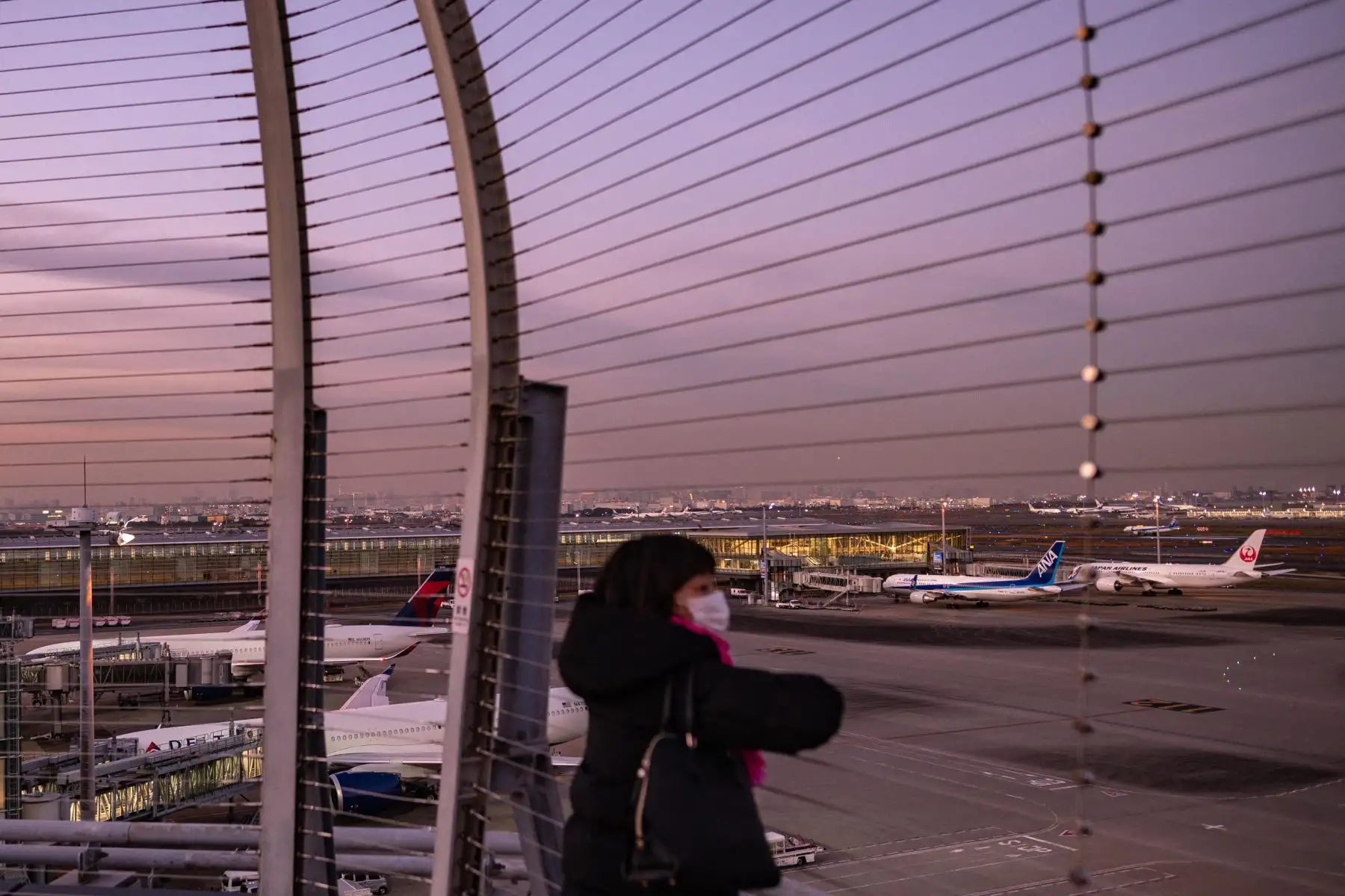 Una mujer mira desde la plataforma de observación del aeropuerto internacional Haneda de Tokio, cuando Japón anunció planes para prohibir a todos los nuevos viajeros extranjeros la variante Omicron de Covid-19. Foto: AFP