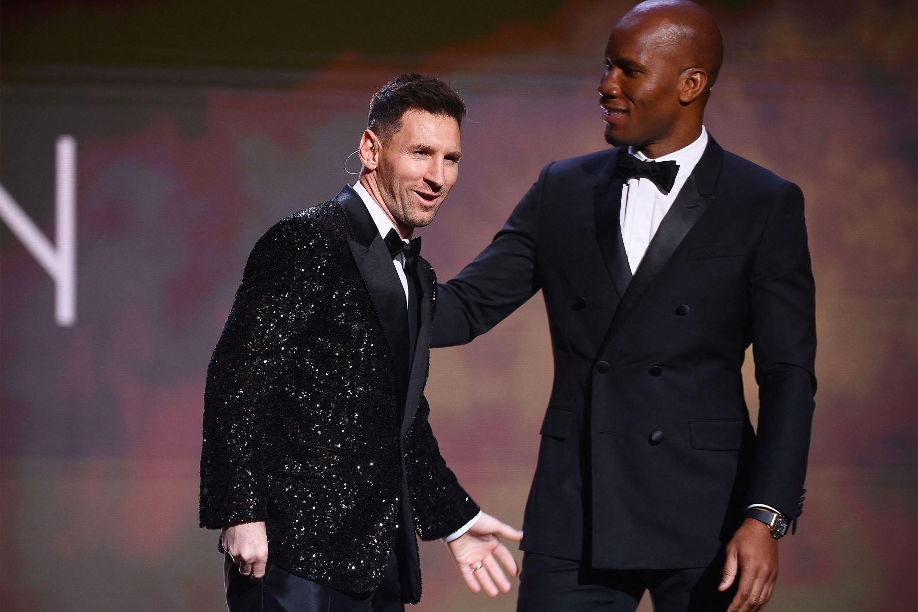 El delantero argentino del Paris Saint-Germain Lionel Messi saluda al exjugador de fútbol de Costa de Marfil y presentador nocturno Didier Drogba después de recibir el premio Ballon d