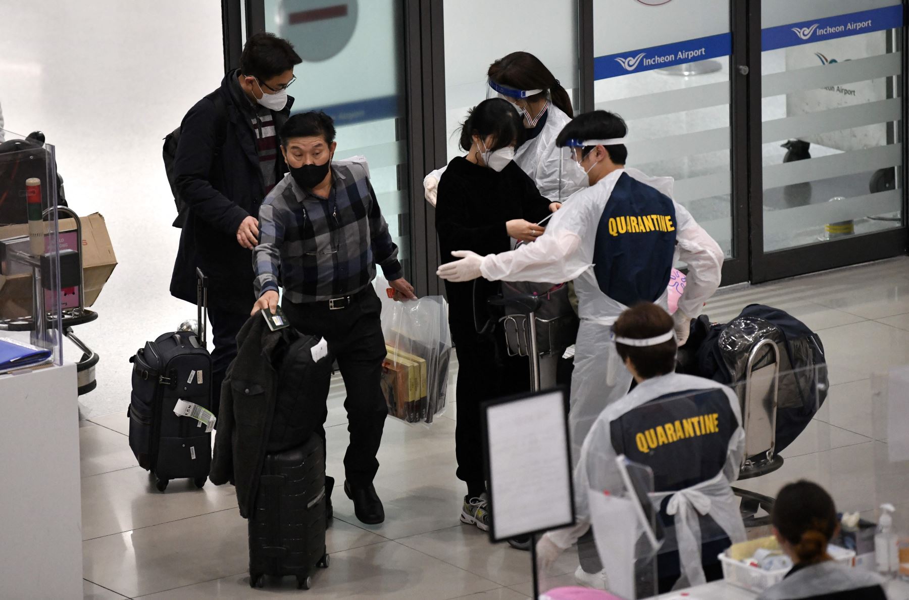 Personal que usa equipo de protección guían a los viajeros en la sala de llegadas del Aeropuerto Internacional de Incheon, en medio de crecientes preocupaciones sobre la variante ómicron Covid-19. Foto: AFP