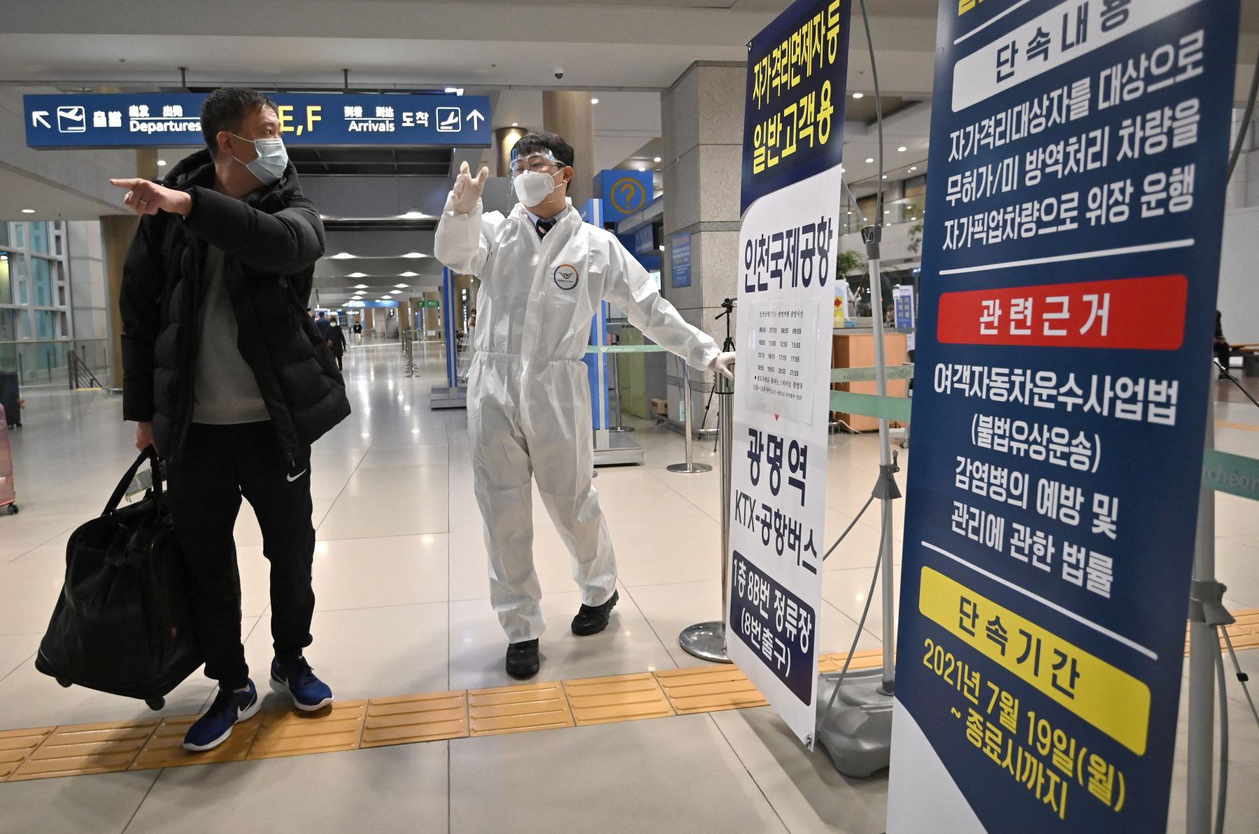 Personal que usa equipo de protección guían a los viajeros en la sala de llegadas del Aeropuerto Internacional de Incheon, en medio de crecientes preocupaciones sobre la variante ómicron Covid-19. Foto: AFP