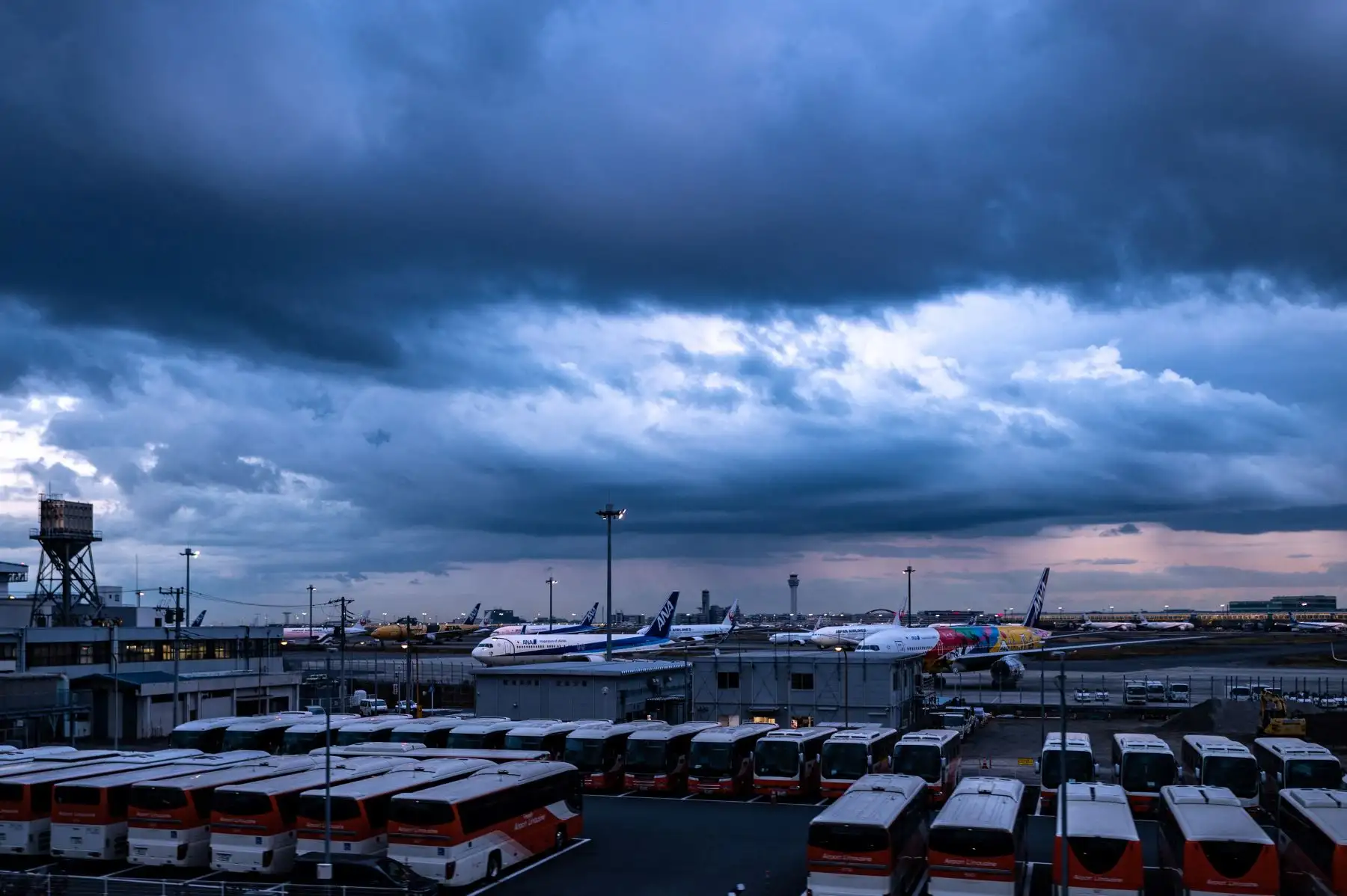Las aeronaves se muestran detrás de los autobuses a través de la ventana de un tren de la línea del aeropuerto Haneda, un día después de que Japón anunciara que restablecería las estrictas medidas fronterizas, salvo todas las nuevas llegadas extranjeras sobre la variante ómicron Covid. Foto: AFP