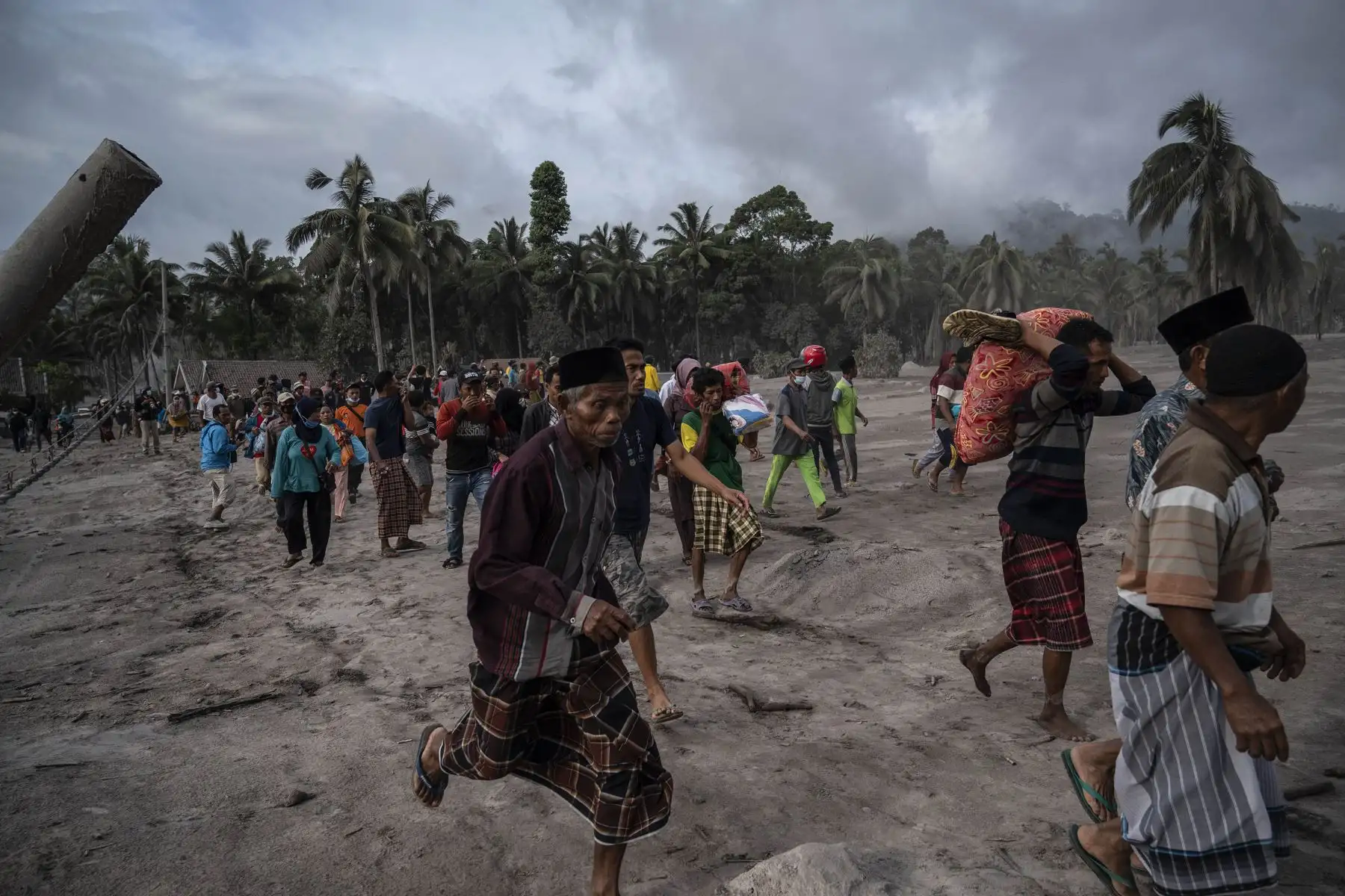 Un grupo de aldeanos rescatan sus pertenencias en un área cubierta de ceniza volcánica, en la aldea de Sumber Wuluh, en Lumajang, Indonesia. Foto: AFP