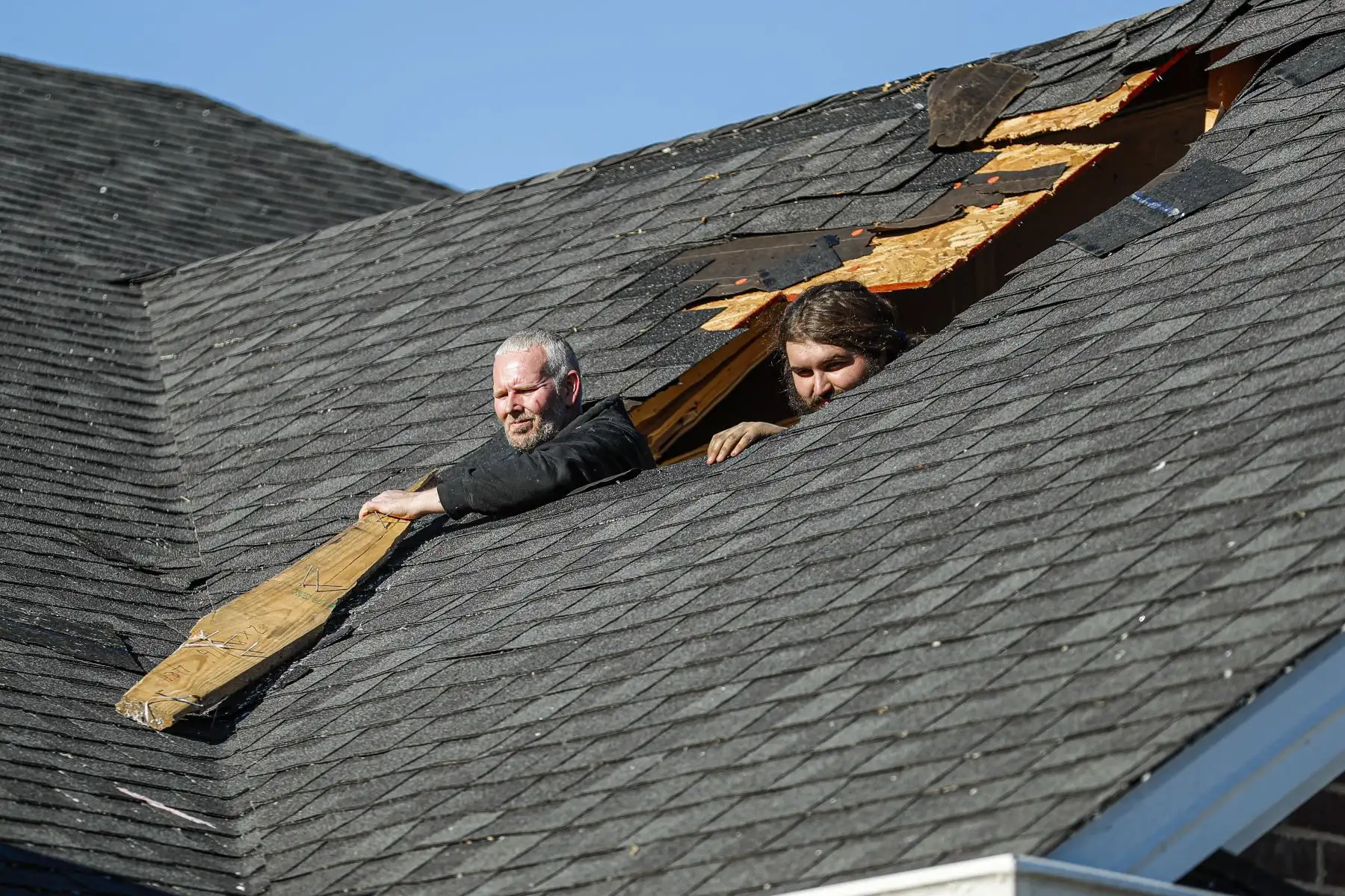 Timmy Tomes (izquierda) y Dalton Finn (Ri) miran a través de lo que queda del techo de un amigo después de que el clima extremo azotara el área, en Bowling Green, Kentucky, el 13 de diciembre de 2021. Foto: AFP