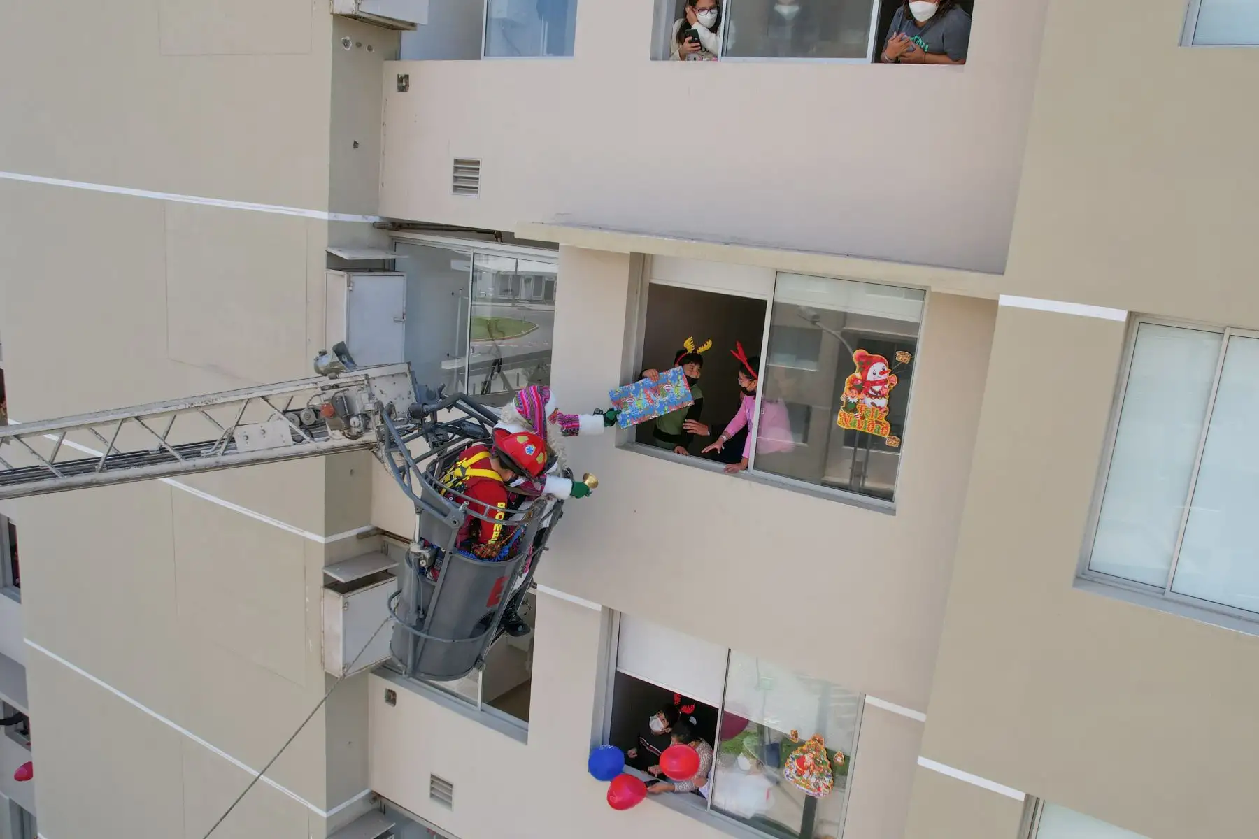 A pocos días de celebrarse la Navidad, Paul Suarez, el Papá Noel peruano, visitó la Villa Panamericana para llevar magia, color y alegría a más de 120 niños con Covid-19 que se encuentran aislados en este centro de atención. Con apoyo de una escalera telescópica de la Compañía de Bomberos, el navideño personaje llegó hasta los pisos más altos de las torres de la Villa para que ningún menor se quede sin obsequio. 
Foto: ANDINA/Jhonel Rodríguez