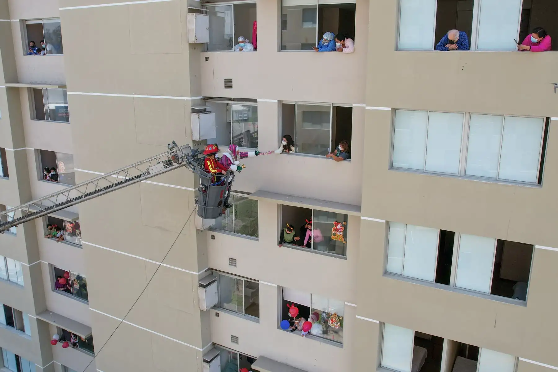 A pocos días de celebrarse la Navidad, Paul Suarez, el Papá Noel peruano, visitó la Villa Panamericana para llevar magia, color y alegría a más de 120 niños con Covid-19 que se encuentran aislados en este centro de atención. Con apoyo de una escalera telescópica de la Compañía de Bomberos, el navideño personaje llegó hasta los pisos más altos de las torres de la Villa para que ningún menor se quede sin obsequio. 
Foto: ANDINA/Jhonel Rodríguez