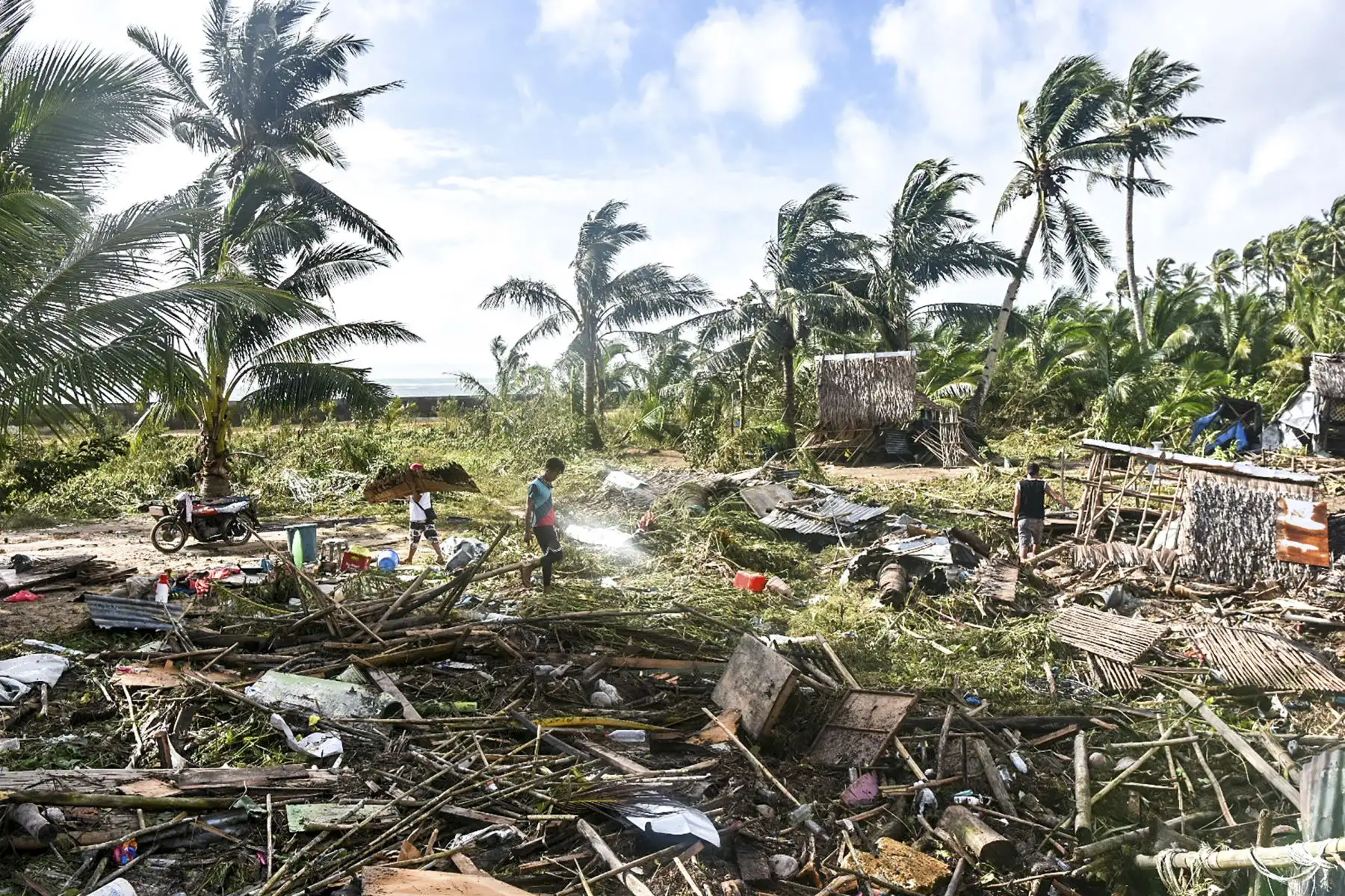 Residentes caminan frente a los escombros de sus viviendas que fueron arrasadas tras el paso del tifón Rai, en la ciudad de Hernani, provincia de Samar oriental, en Filipinas. Foto: AFP