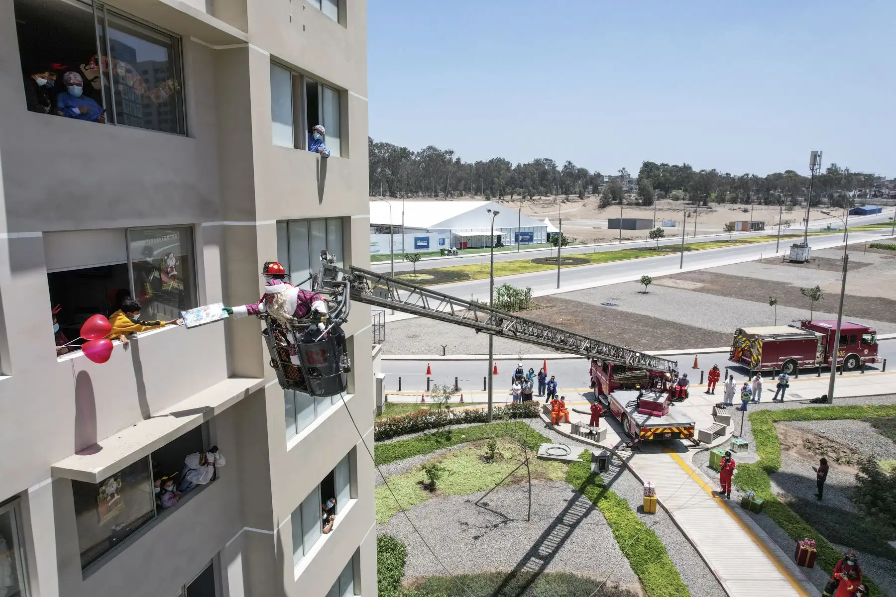A pocos días de celebrarse la Navidad, Paul Suarez, el Papá Noel peruano, visitó la Villa Panamericana para llevar magia, color y alegría a más de 120 niños con Covid-19 que se encuentran aislados en este centro de atención. Con apoyo de una escalera telescópica de la Compañía de Bomberos, el navideño personaje llegó hasta los pisos más altos de las torres de la Villa para que ningún menor se quede sin obsequio. Foto: ANDINA/Jhonel Rodríguez