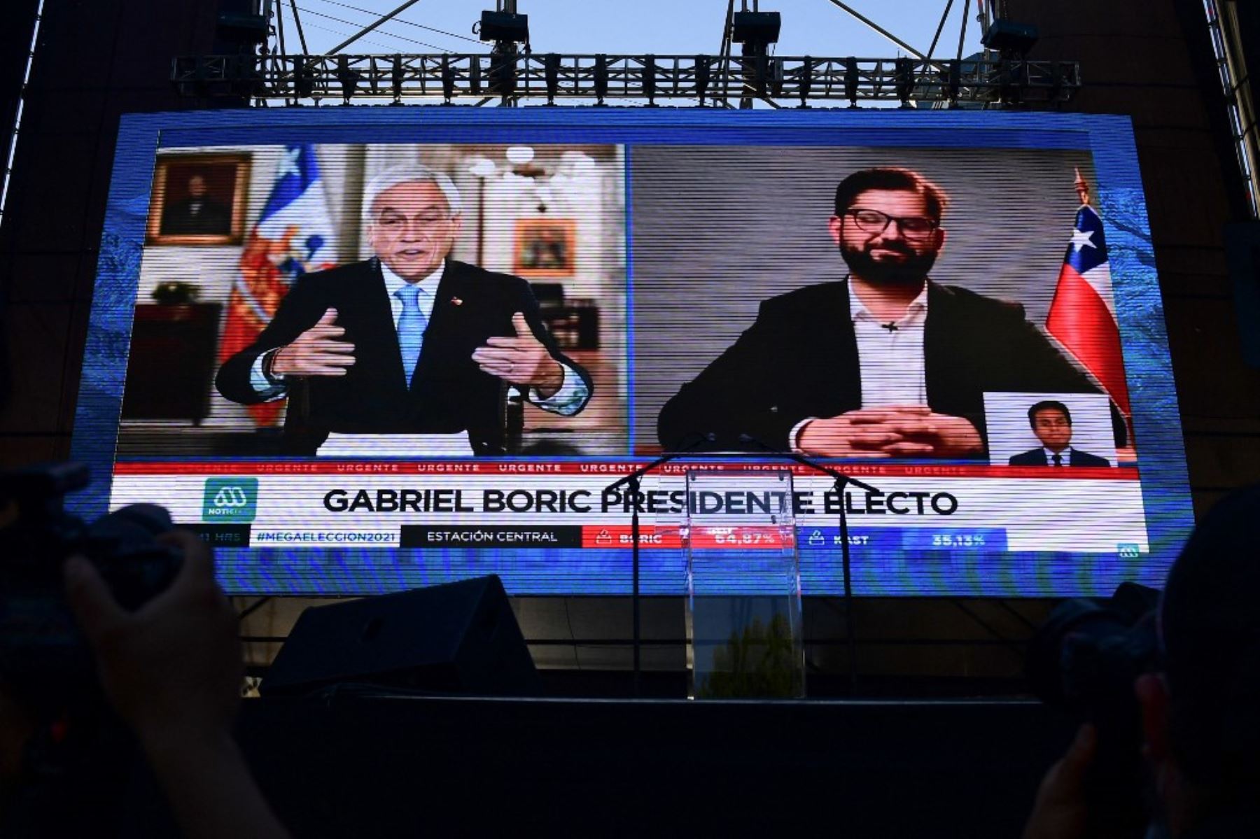 Vista de una pantalla gigante que muestra al presidente chileno Sebastián Piñera (izq.) felicitando al candidato presidencial chileno Gabriel Boric, del partido Apruebo Dignidad, luego de los primeros resultados oficiales de la segunda vuelta de las elecciones presidenciales, en Santiago, el 19 de diciembre de 2021. Foto: AFP