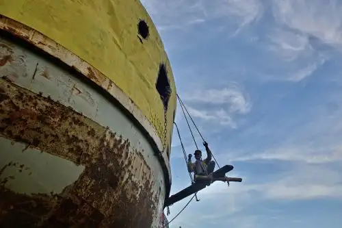 Un trabajador de un astillero realiza trabajos de mantenimiento en un barco. Foto: AFP/Archivo