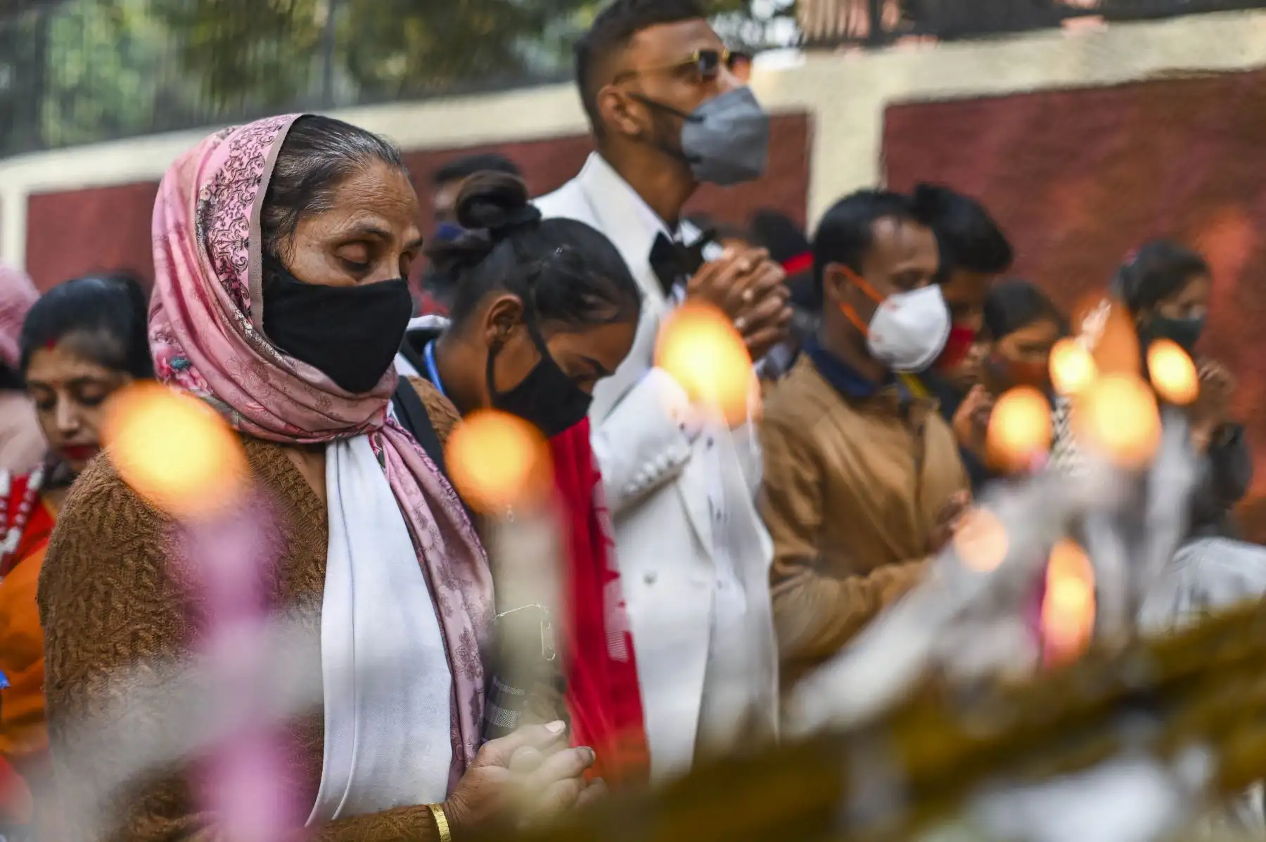 Los devotos cristianos oran después de colocar velas en una barricada policial fuera de la Catedral del Sagrado Corazón, cerrada al público en general debido a la pandemia del coronavirus Covid-19, durante las celebraciones navideñas en Nueva Delhi el 25 de diciembre de 2021 Foto: AFP