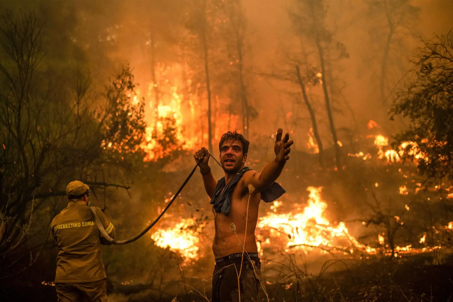 Un residente local hace un gesto mientras sostiene una manguera de agua vacía durante un intento de extinguir los incendios forestales que se acercan al pueblo de Pefki en la isla de Evia (Eubea), la segunda isla más grande de Grecia, el 8 de agosto de 2021. 
Foto: AFP