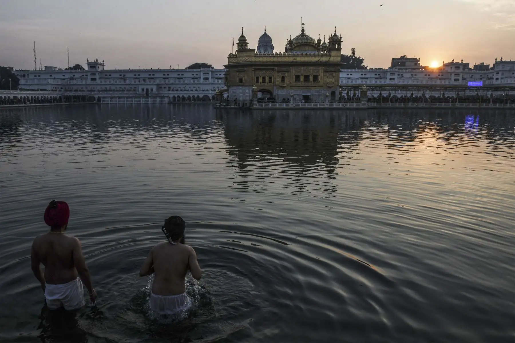 Los devotos  se bañan en el sagrado Sarovar  durante la última puesta de sol de 2021 en la víspera del Año Nuevo 2022, en el Templo Dorado del santuario sij en Amritsar el 31 de diciembre de 2021.
Foto: AFP