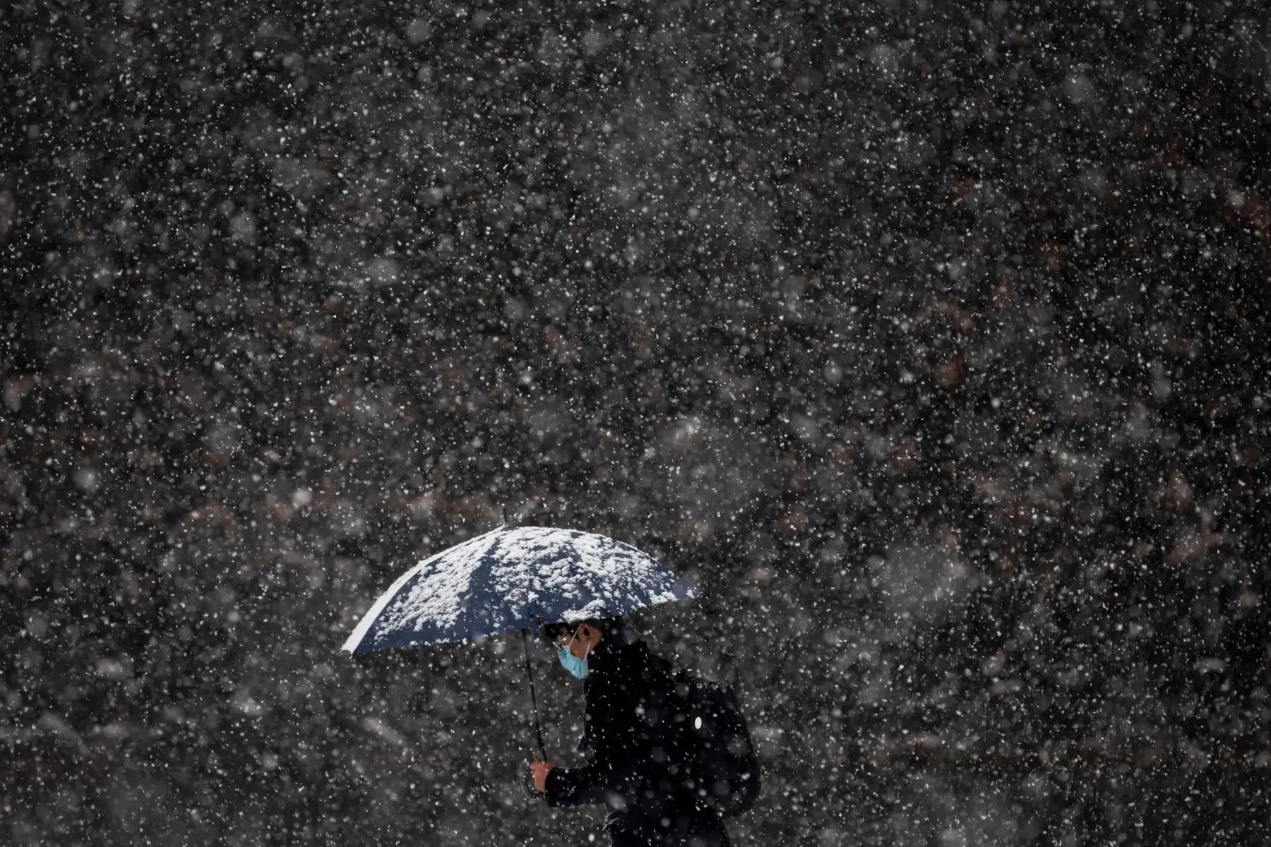 Un peatón camina con un paraguas mientras cae nieve cerca del Palacio Imperial en Tokio. Foto: AFP