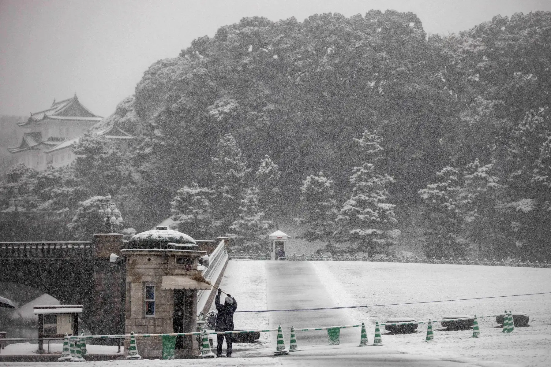 Un guardia cepilla la nieve caída de un toldo fuera del Palacio Imperial en Tokio. Foto: AFP