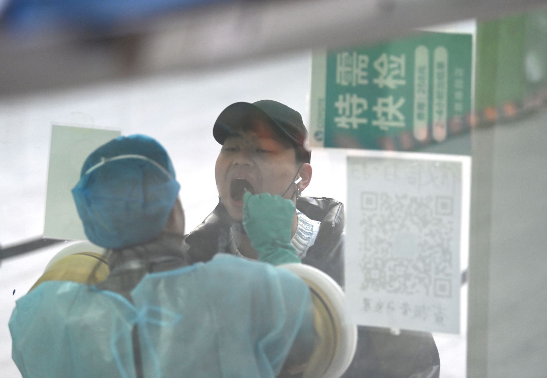 Un trabajador de la salud toma muestra con un hisopo a un hombre para descartar el coronavirus en una estación de recolección de ácido nucleico en Beijing el 6 de diciembre del 2021.Foto: AFP