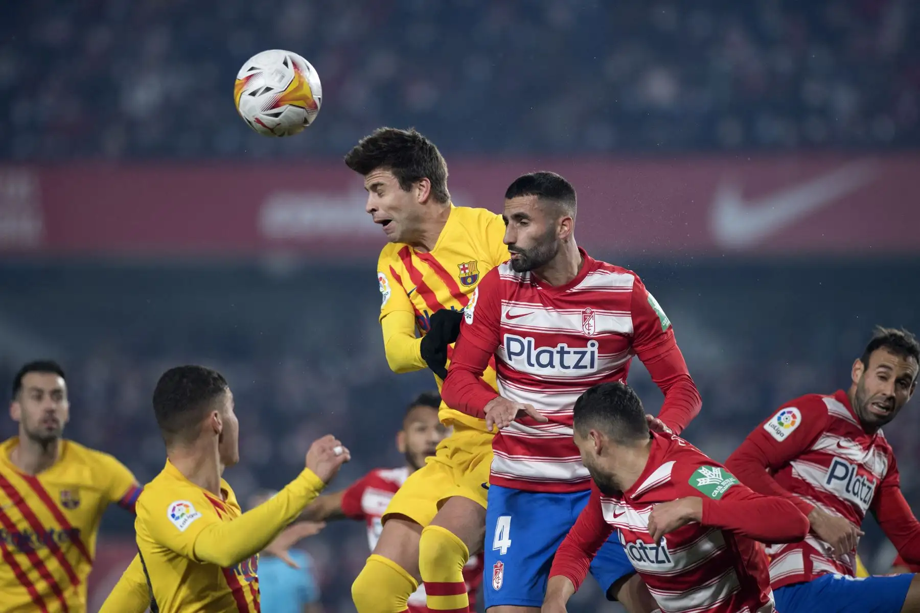 El defensa español del Barcelona, Gerard Piqué, compite por un cabezazo con el centrocampista francés del Granada, Maxime Gonalons, durante el partido de la Liga. Foto: AFP