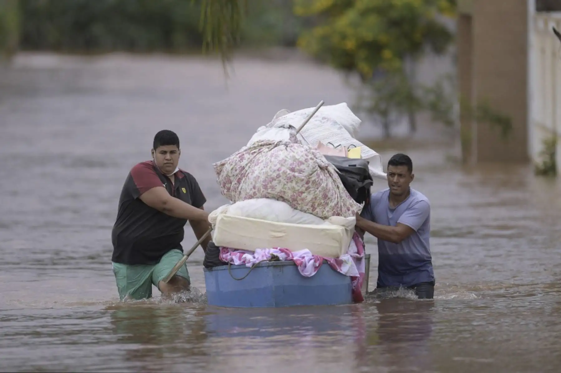 Personas cruzan una calle inundada llevando sus pertenencias a causa de las inundaciones en el municipio brasileño de Juatuba, ubicado en el estado de Minas Gerais, el 10 de enero de 2022, luego de que en los últimos días cayeran lluvias torrenciales en la parte sureste del país. país. Foto: AFP