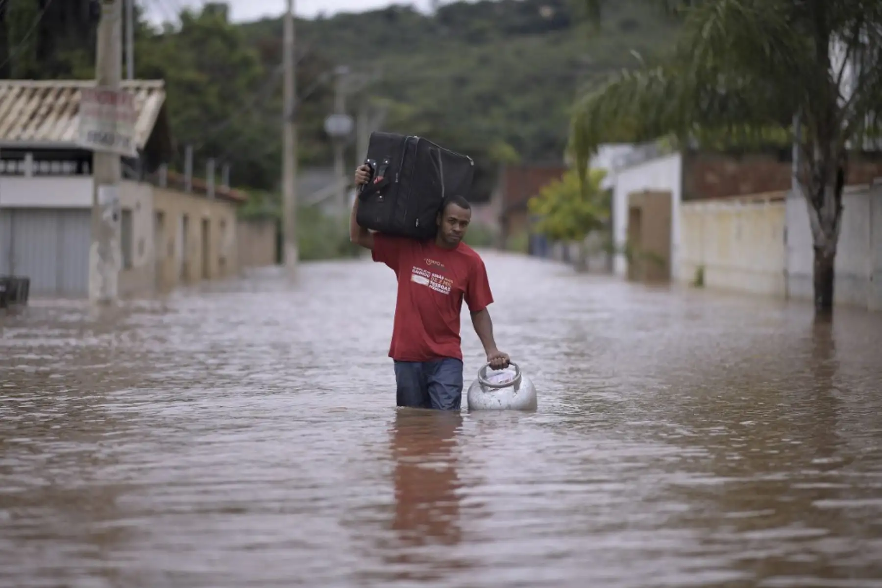 Un hombre cruza una calle inundada llevando sus pertenencias a causa de las inundaciones en el municipio brasileño de Juatuba, ubicado en el estado de Minas Gerais, el 10 de enero de 2022, luego de que en los últimos días cayeran lluvias torrenciales en la parte sureste del país. país. Foto: AFP