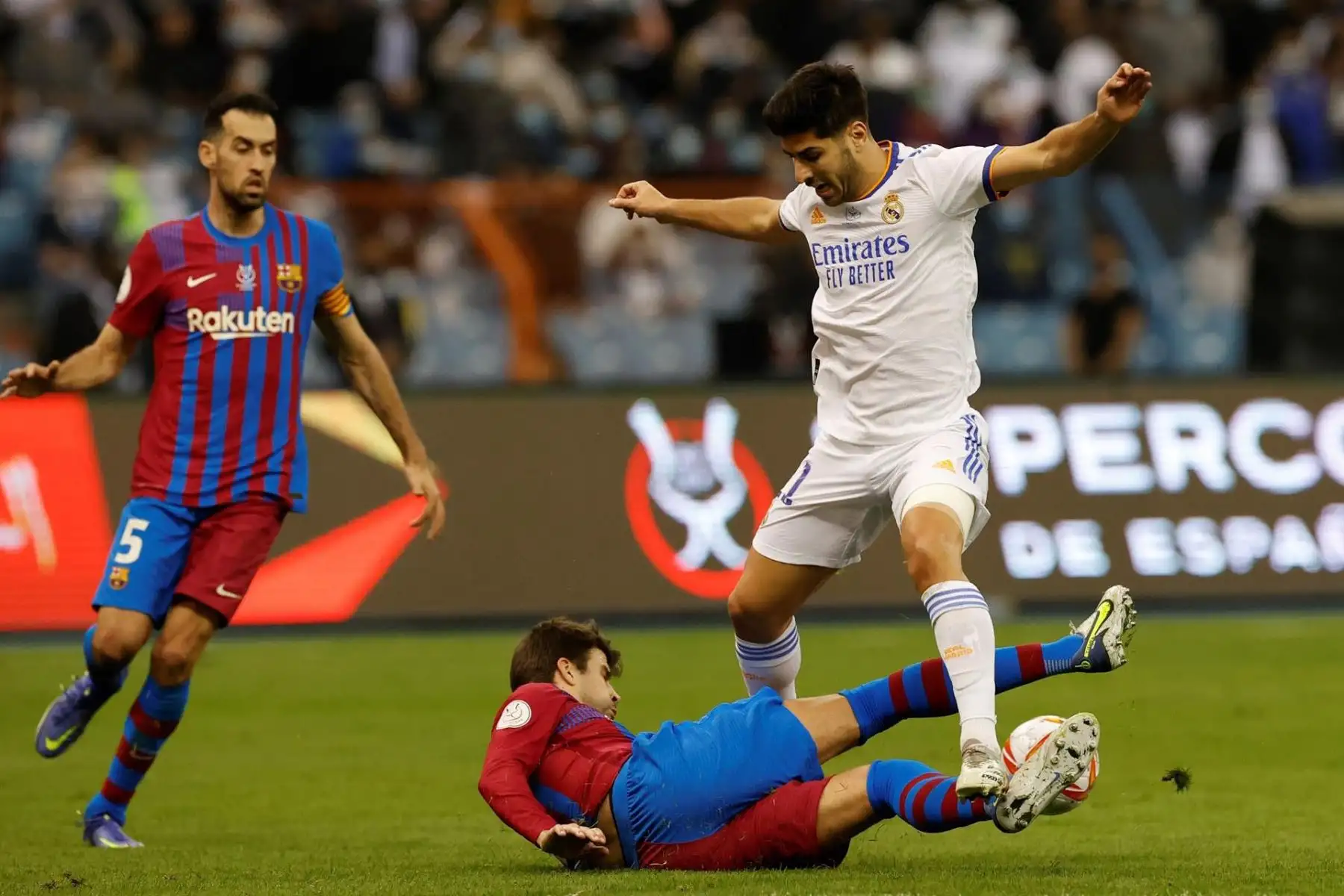 El centrocampista del Real Madrid, Marco Asensio, intenta llevarse el balón ante el defensa del FC Barcelona, Gerard Piqué, durante el encuentro correspondiente a la semifinal de la Supercopa de España que disputan en el estadio Ray Fahd de Riyahd. Foto: EFE