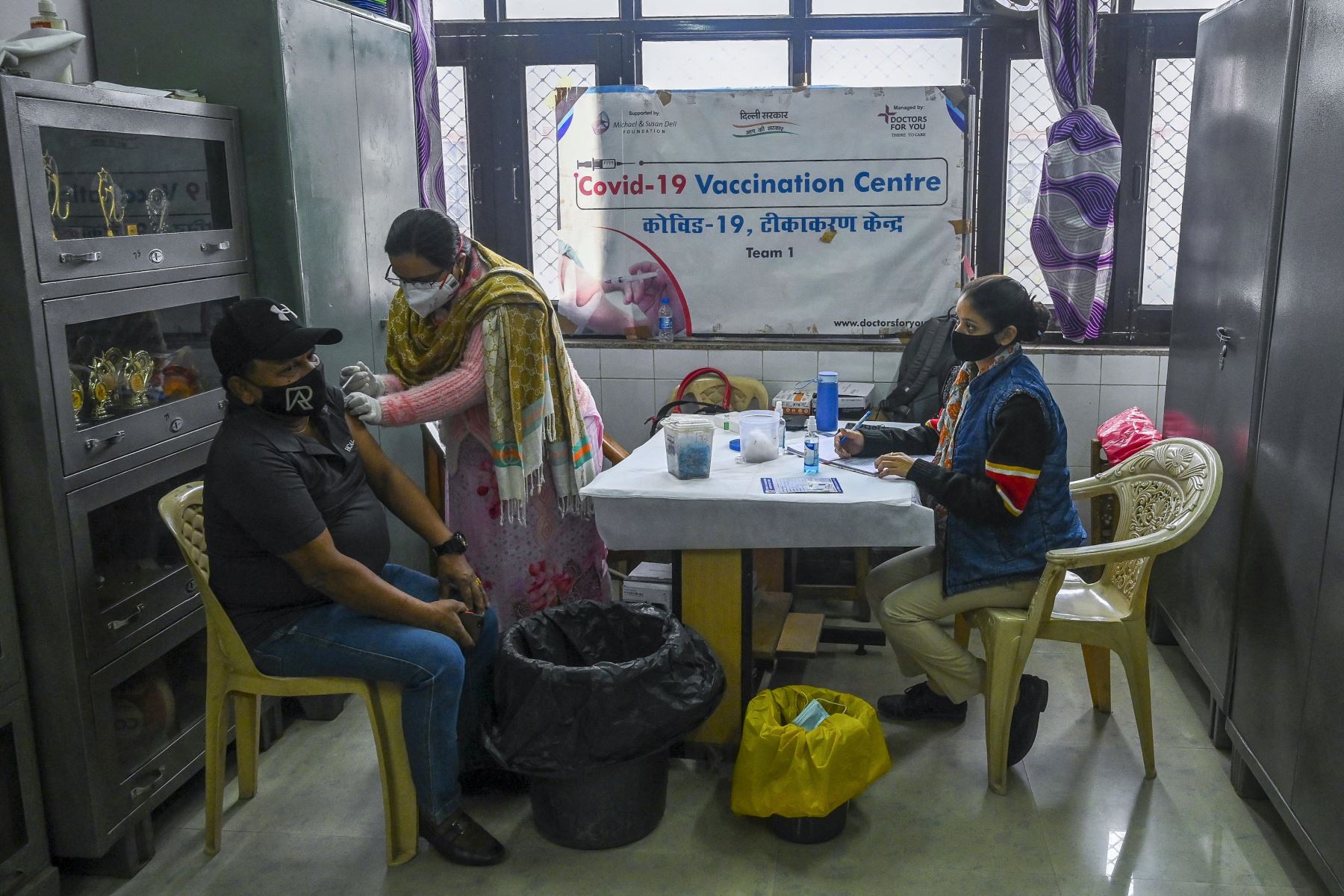 Un trabajador de la salud, inocula a un hombre con una dosis de la vacuna Covishield contra el coronavirus Covid-19 en un centro de vacunación instalado temporalmente en una escuela en Nueva Delhi. Foto: AFP