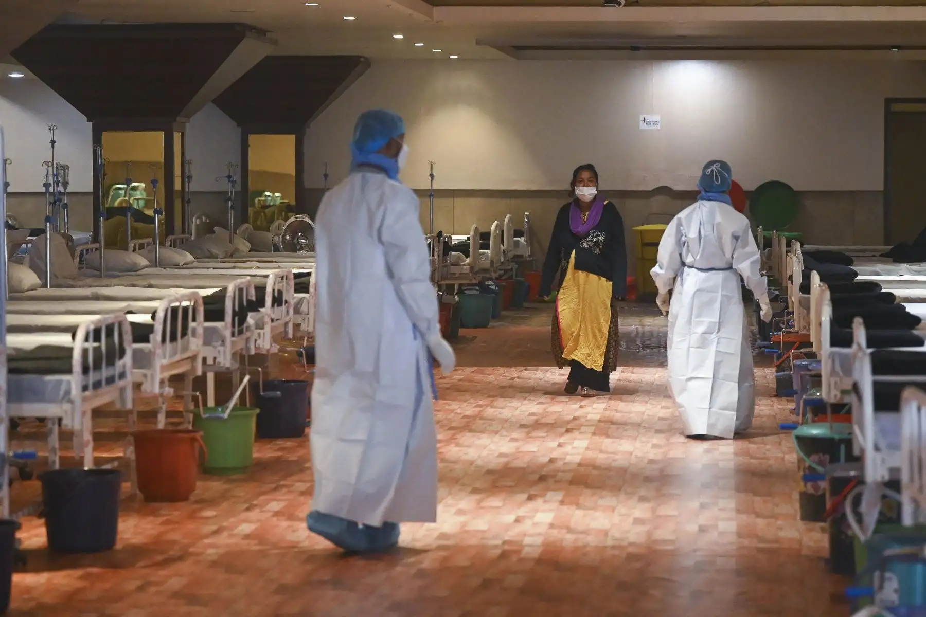 Los trabajadores de la salud pasan junto a un paciente dentro de un salón de banquetes convertido temporalmente en un centro de atención del coronavirus Covid-19 en Nueva Delhi. Foto: AFP