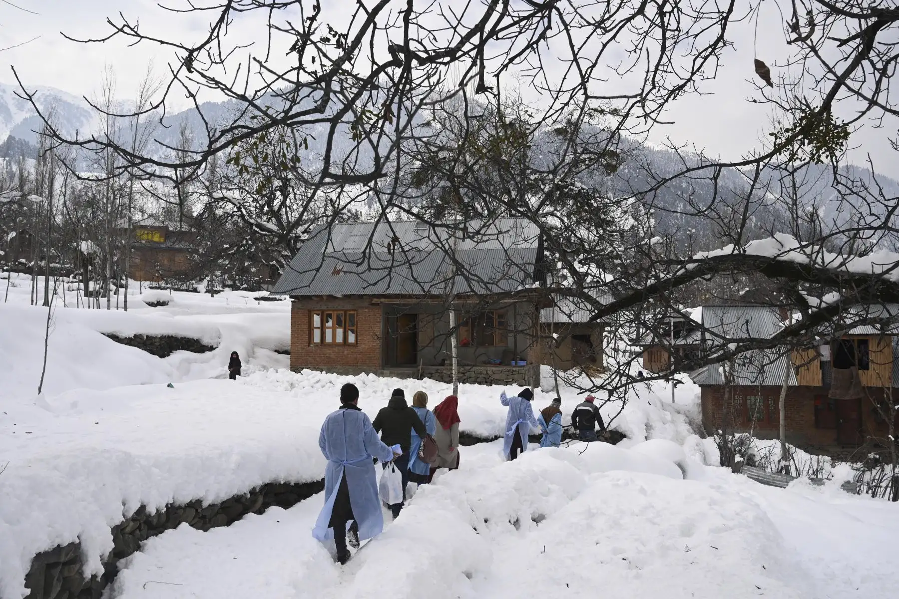 Los trabajadores de la salud caminan por una carretera cubierta de nieve durante una campaña de vacunación puerta a puerta contra el coronavirus Covid-19 en la aldea de Khag en el distrito de Budgam, a unos 55 km de Srinagar. Foto: AFP