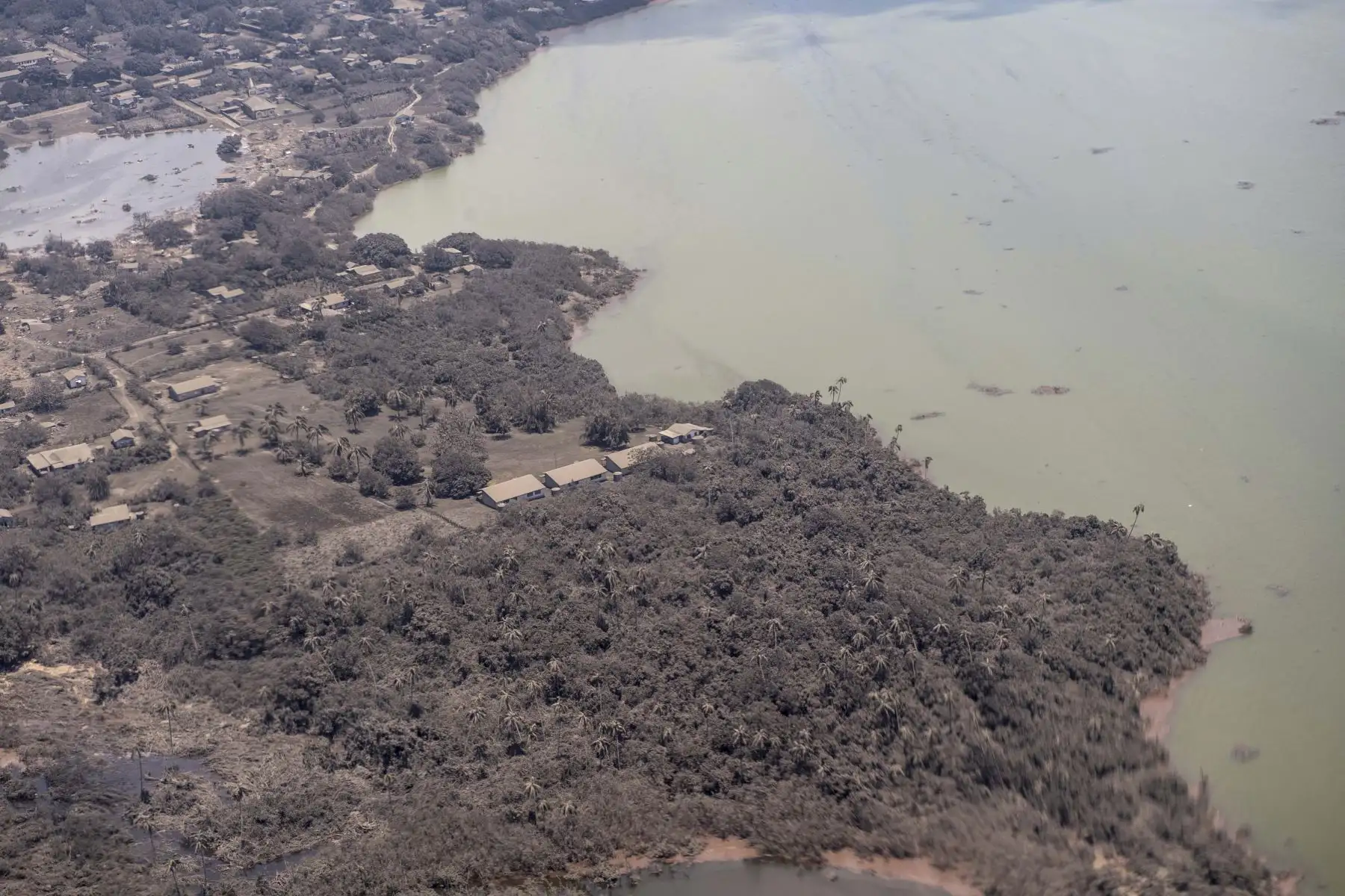 Una foto proporcionada por la Fuerza de Defensa de Nueva Zelanda (NZDF) muestra una vista aérea de un avión P-3K2 Orion mientras sobrevuela un área de Tonga, el 17 de enero de 2022 (emitida el 18 de enero de 2022), con ceniza en los techos de las viviendas y la vegetación circundante. Foto: EFE