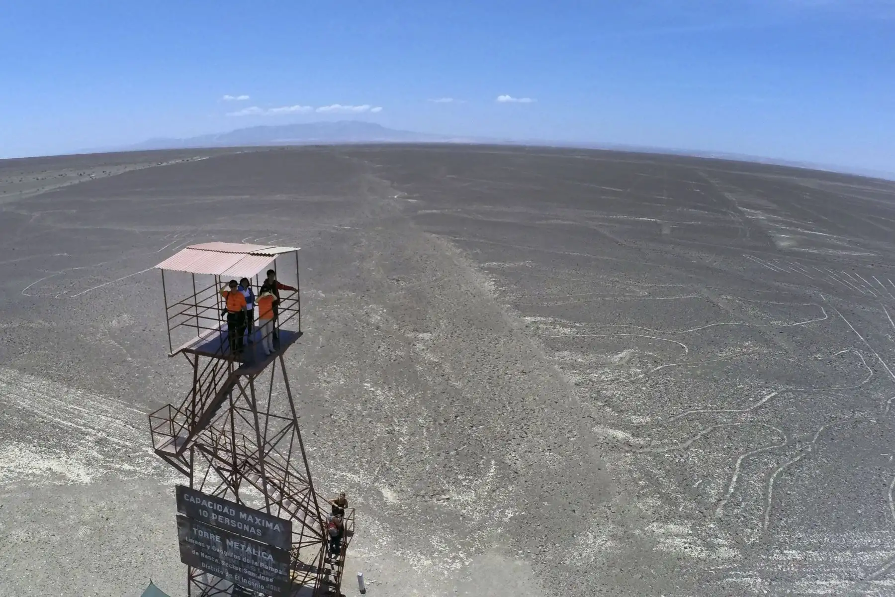 Los turistas en lo alto de un mirador admiran las Líneas de Nazca en Nazca, Ica, Perú, a unos 435 km al sur. Los geoglifos solo se pueden ver desde lo alto de las colinas circundantes o desde aviones. Foto: AFP