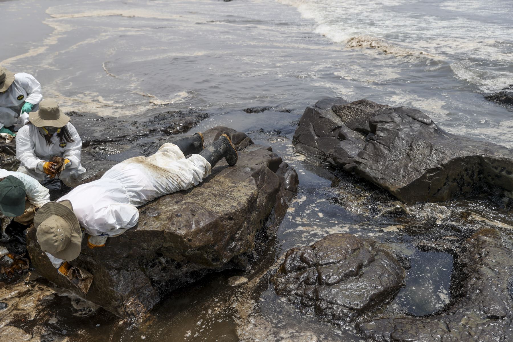 Un obrero contratado por Repsol intenta retirar el petróleo de las rocas en la playa Cavero en Ventanilla. Foto: ANDINA/Jhonel Rodríguez Robles