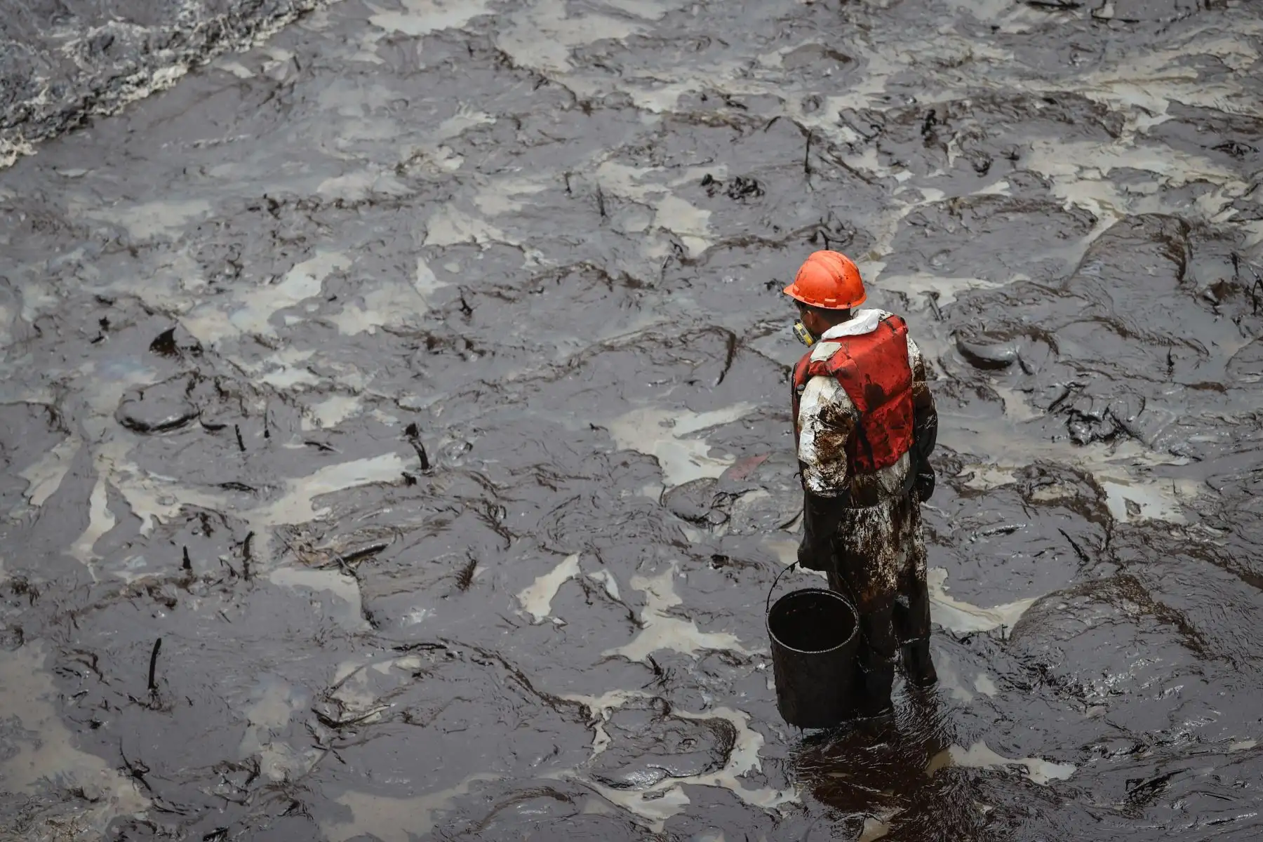 Una foto desoladora. Con solo un balde, como herramienta, un trabajador contratado para ayudar en la limpieza del mar de Ventanilla, a causa del derrame de petróleo, trata de recoger el crudo que cada vez se extiende más hacia las playas del norte chico. Foto: ANDINA/Andrés Valle
