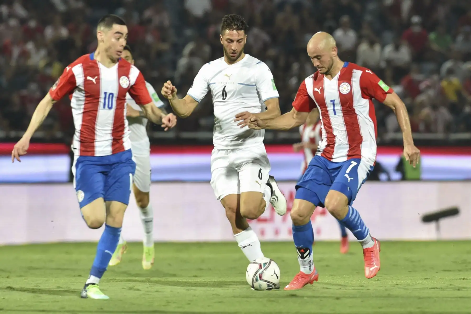 Rodrigo Bentancur (centro) de Uruguay compite por el balón con Miguel Almiron (izq.) y Carlos González (der.) de Paraguay durante un partido de clasificación para la Copa Mundial de la FIFA Qatar 2022 en el estadio General Pablo Rojas de Asunción. Foto: AFP
