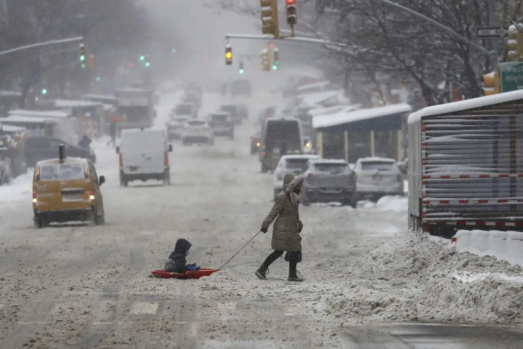Una mujer transita junto a su hijo a través de un trineo en medio de la tormenta de nieve, en Nueva York, Estados Unidos. Foto: EFE