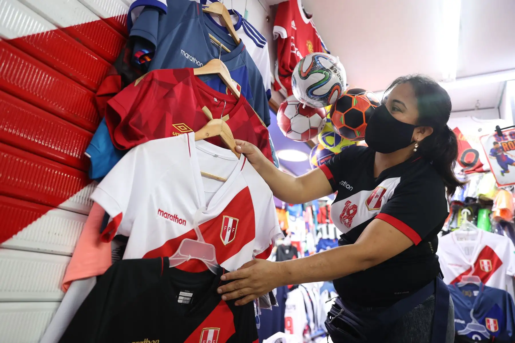 Una comerciante exhibe camisetas con los colores de la selección peruana en Gamarra, el emporio textil más importante de Sudamérica, a 24 horas del partido Perú-Ecuador por la clasificación a Catar 2022. En la cresta de la tercera ola de la pandemia de coronavirus, el gobierno peruano autorizó para este encuentro un aforo de 70 % en el Estadio Nacional, al que podrán ingresar solamente personas con dos vacunas y una dosis de refuerzo contra la covid-19. Foto: ANDINA/Jhonel Rodríguez
