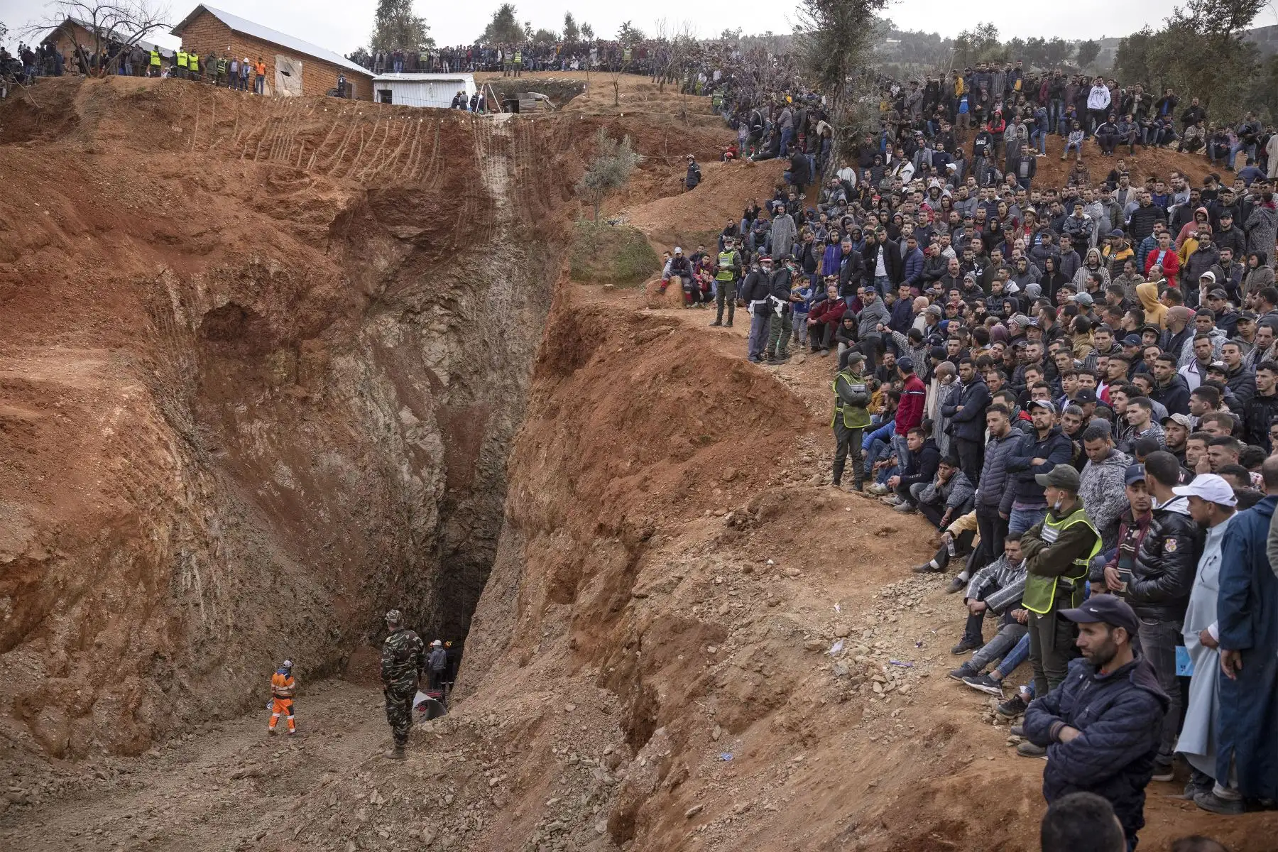 Los transeúntes observan cómo los equipos de emergencia marroquíes trabajan para rescatar a Rayan, un niño de cinco años, quien cayo a un pozo.
Foto: AFP