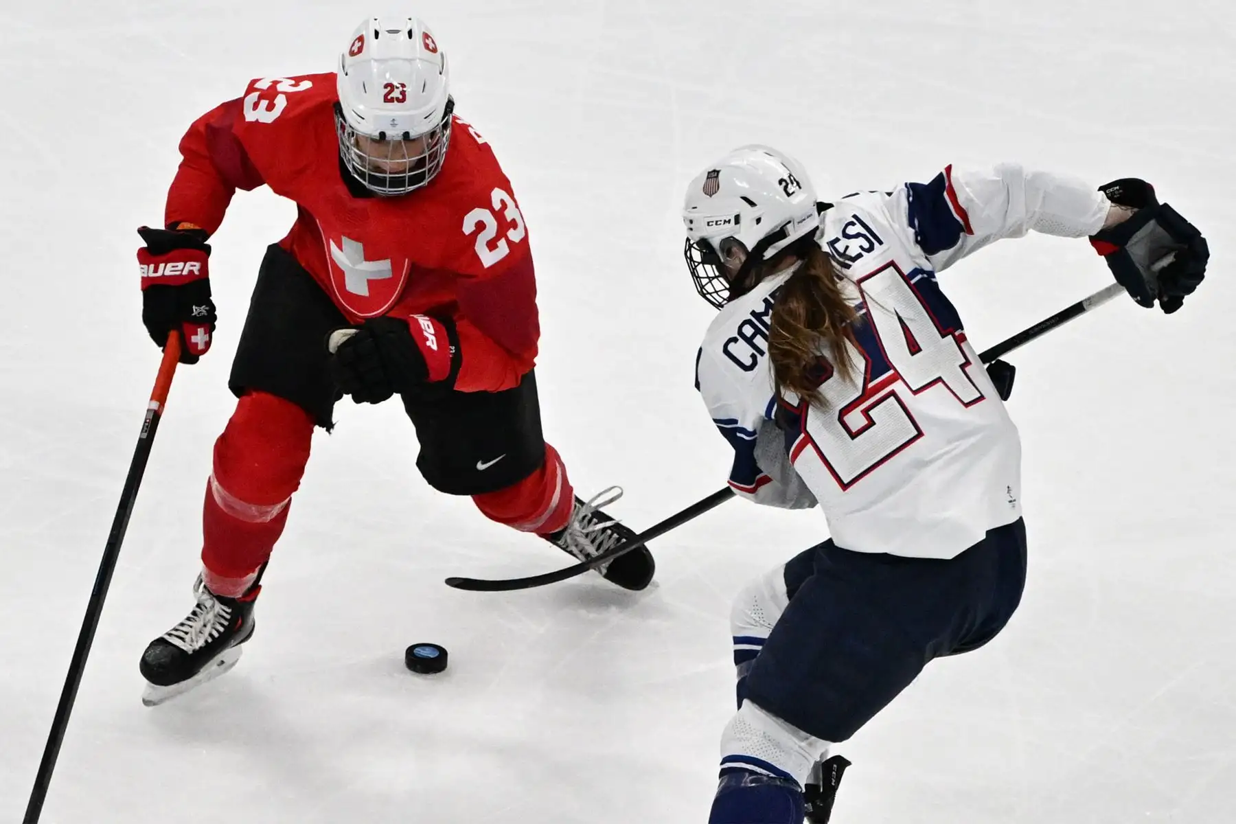 La estadounidense Danielle Cameranesi es desafiada por la suiza Nicole Bullo durante el partido del grupo A de la ronda preliminar femenina de la competencia de hockey sobre hielo de los Juegos Olímpicos de Invierno de Beijing 2022,
Foto: AFP