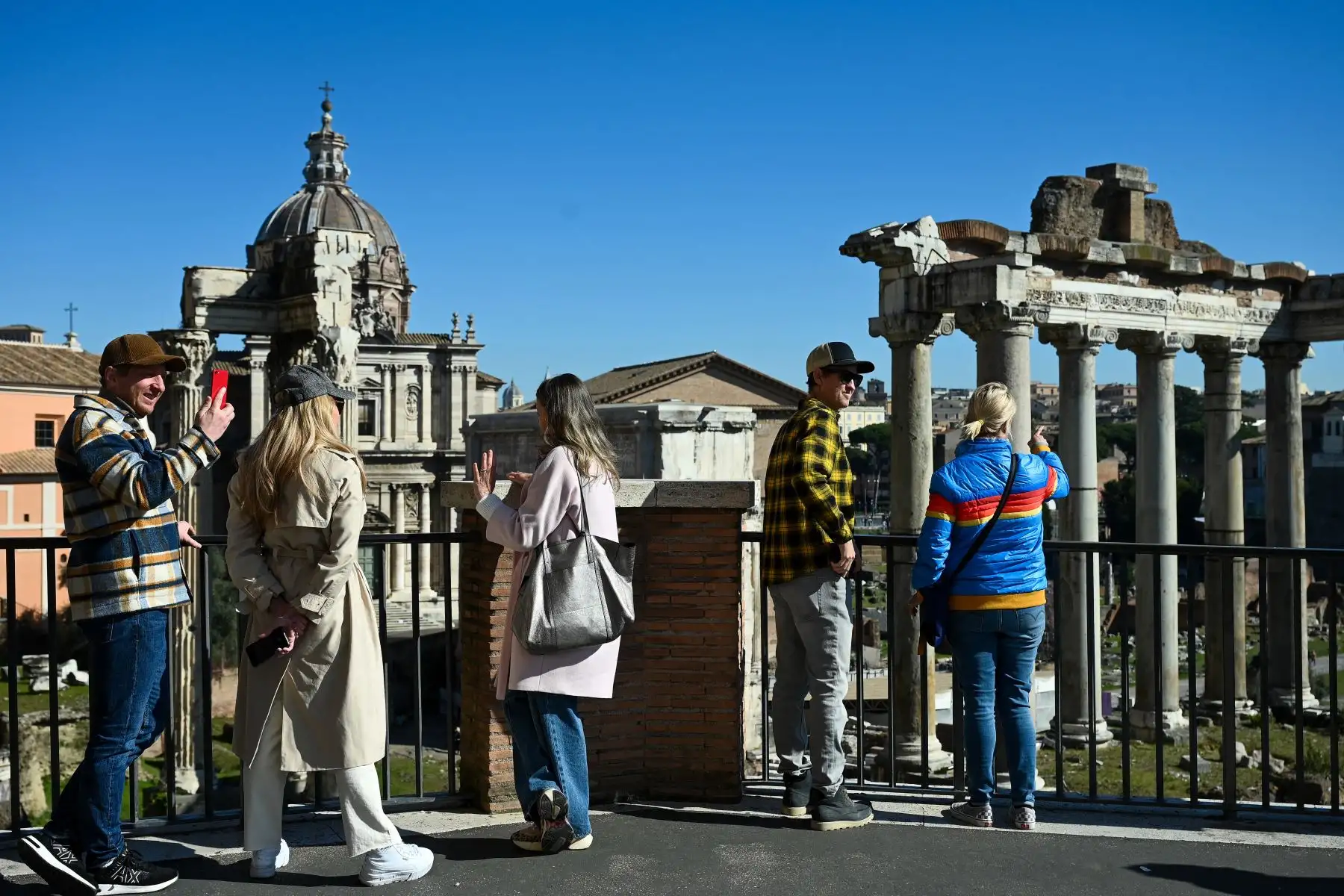 Las personas toman fotografías sin usar una máscara facial, en el Foro Romano en Roma. Foto: AFP