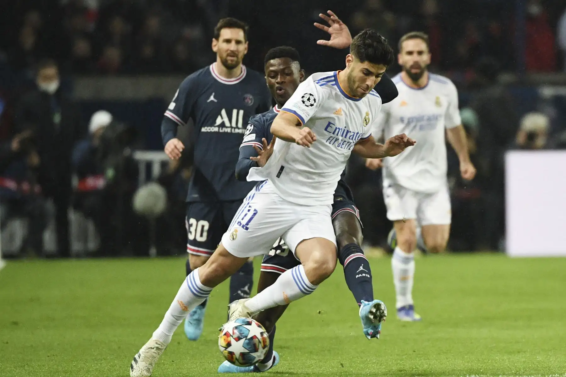 El centrocampista español del Real Madrid, Marco Asensio (R), lucha por el balón con el defensor portugués del Paris Saint-Germain, Nuno Mendes (L), durante el partido de ida de octavos de final de la Liga de Campeones de la UEFA entre el Paris Saint-Germain (PSG) y el Real Madrid en el Estadio Parc des Princes en París el 15 de febrero de 2022. Foto: AFP