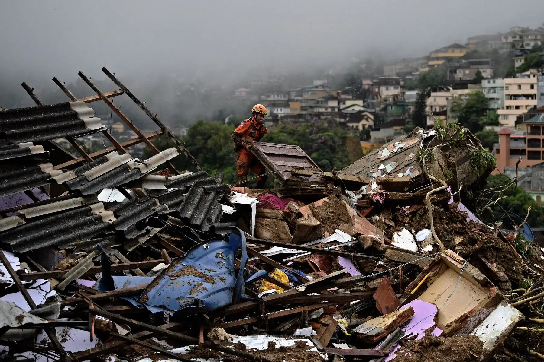 Un miembro del equipo de rescate de los servicios de bomberos levanta escombros para buscar sobrevivientes después de un deslizamiento de tierra en Petrópolis, Brasil. Foto: AFP