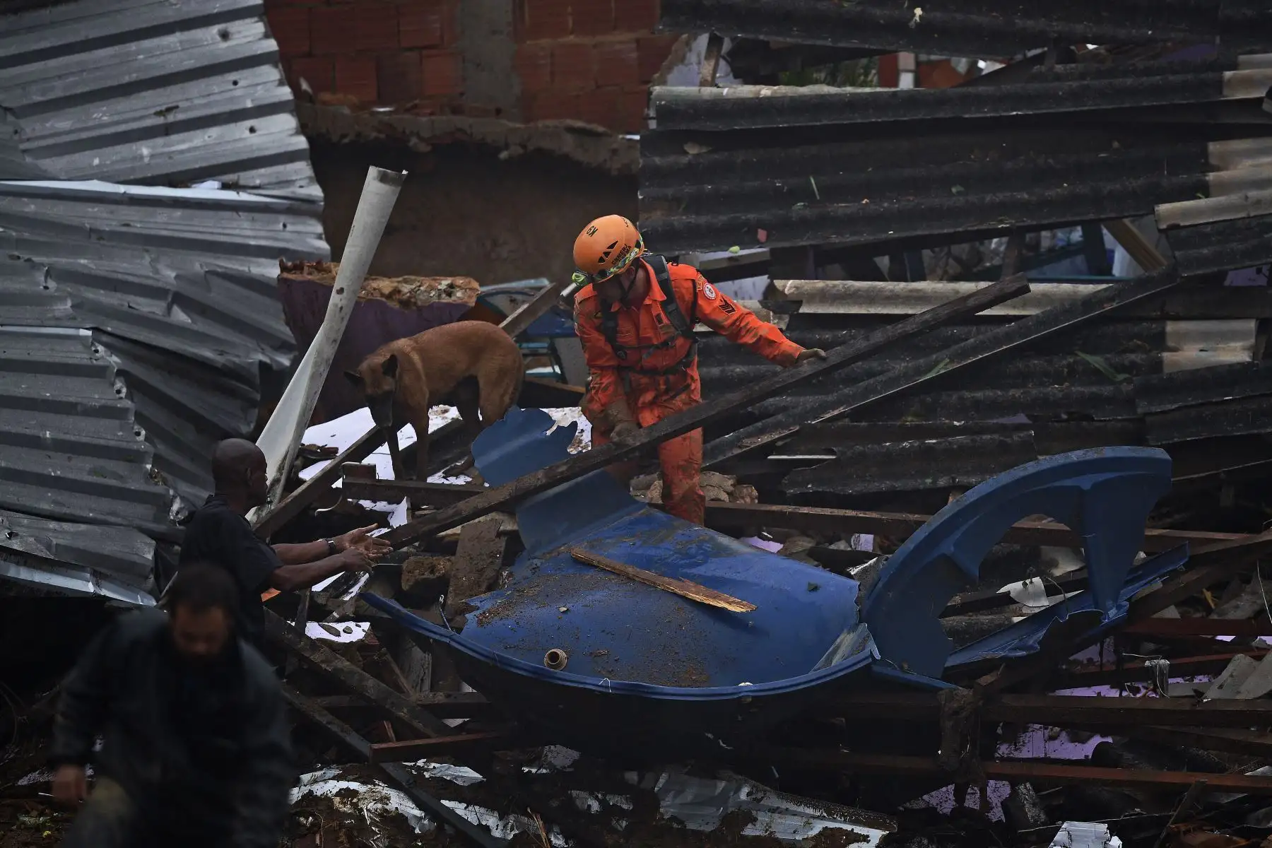 Un miembro del equipo de rescate de los servicios de bomberos levanta escombros para buscar sobrevivientes junto a un perro, después de un deslizamiento de tierra en Petrópolis, Brasil. Foto: AFP