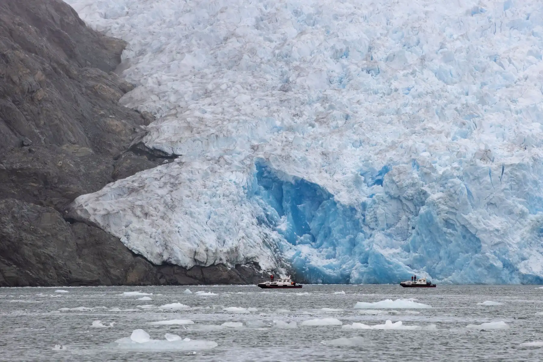 Dos botes pasan frente al glaciar San Rafael, parte de los Campos de Hielo Norte en el Parque Nacional Laguna San Rafael, en la sureña región de Aysén (Chile). El inexorable avance del calentamiento global ha llegado a una de las zonas más prístinas del planeta: la Patagonia chilena, cuyos glaciares batallan sin suerte contra el deshielo. Foto: EFE