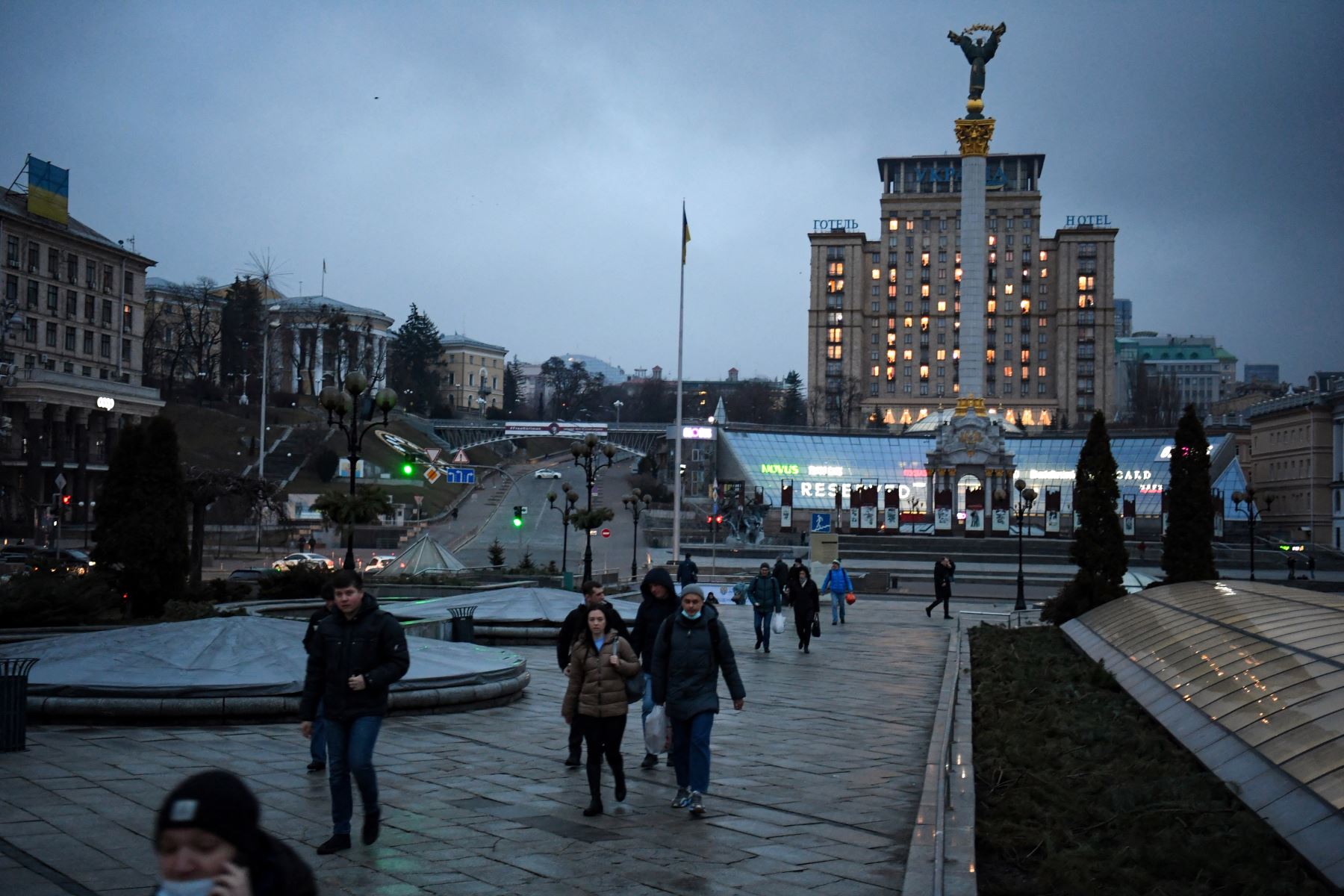 Algunas personas caminan en el centro de Kiev, frente al monumento a la independencia, a primera hora del 24 de febrero del 2022. Foto: AFP.