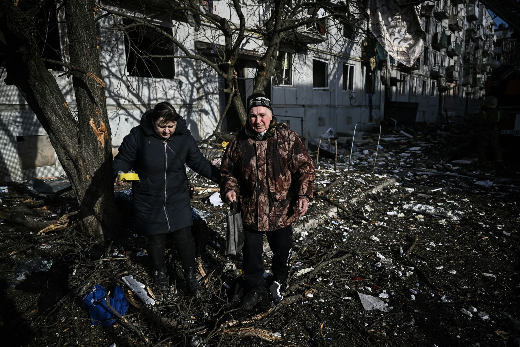 La gente pasa junto al cuerpo de un familiar fuera de un edificio destruido después de los bombardeos en la ciudad de Chuguiv, en el este de Ucrania. Foto: AFP