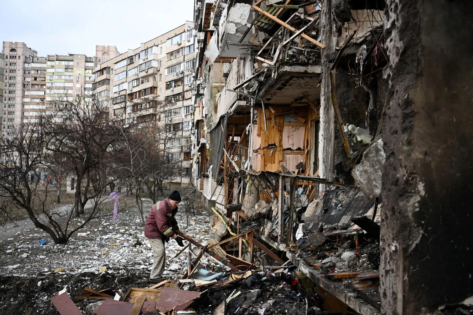 Un hombre limpia los escombros en un edificio residencial dañado en la calle Koshytsa, un suburbio de la capital ucraniana, Kiev, donde supuestamente cayó un proyectil militar. Foto: AFP