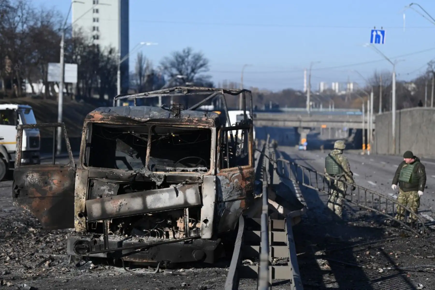 Soldados ucranianos pasan frente a un vehículo del ejército ucraniano quemado en el lado oeste de la capital ucraniana de Kiev el 26 de febrero de 2022. Foto: AFP