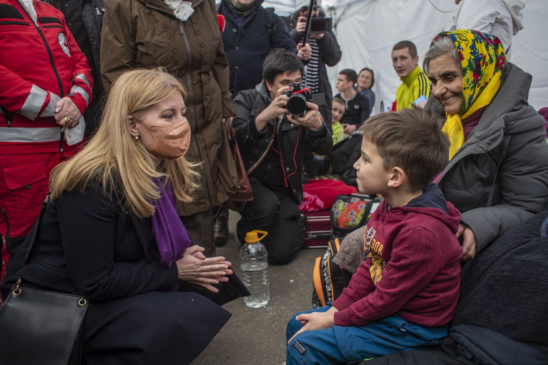La presidenta eslovaca Zuzana Caputova habla con una mujer y un niño ucranianos mientras las personas huyen de Ucrania a Eslovaquia a través del cruce fronterizo de Ubla, Eslovaquia, el 27 de febrero de 2022. Foto: EFE