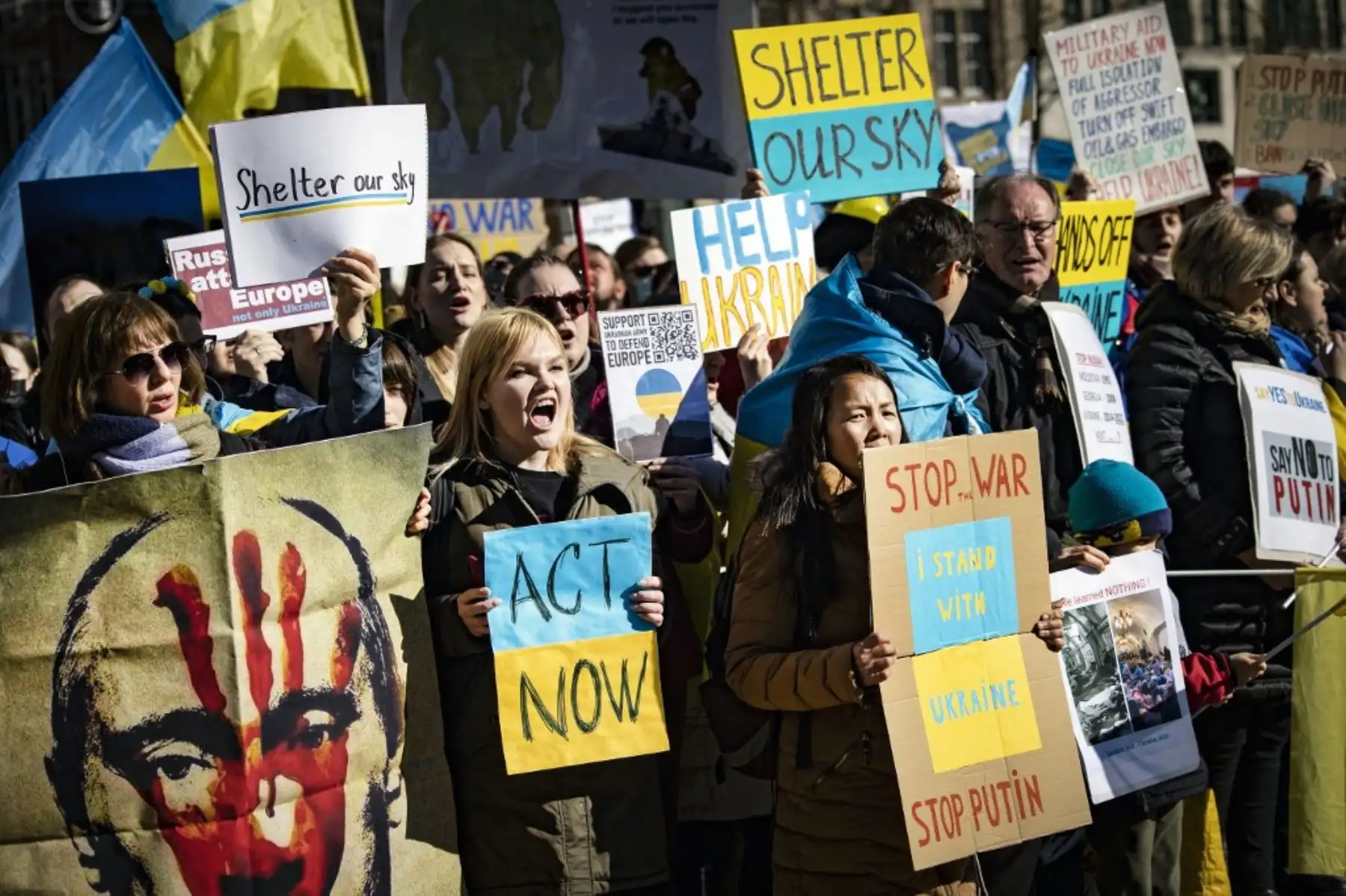 Manifestantes sostienen pancartas y banderas nacionales ucranianas mientras protestan contra la invasión rusa de Ucrania, en la Plaza Dam en Amsterdam el 27 de febrero de 2022. Foto: AFP