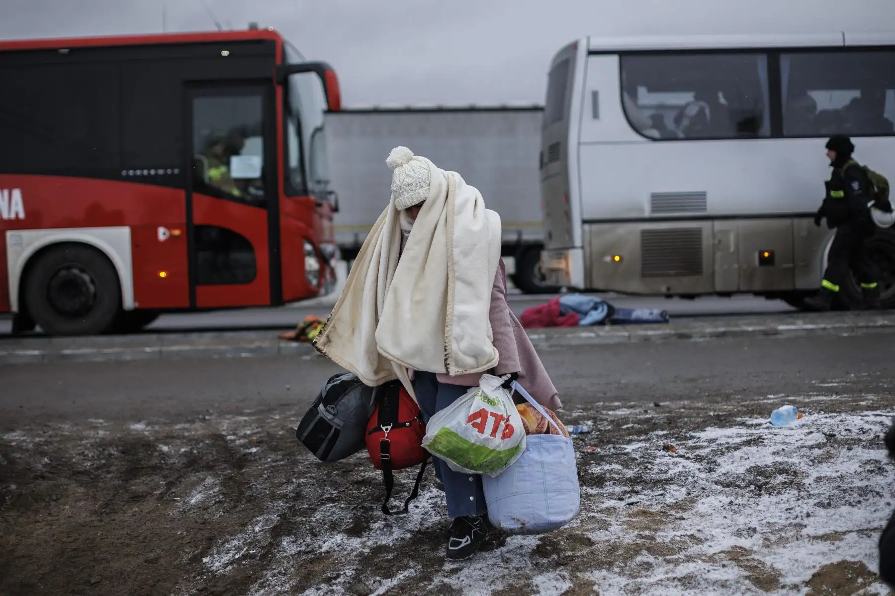 Varias personas procedentes de Ucrania esperan el autobús tras cruzar la frontera con Polonia huyendo de la guerra. Foto: EFE