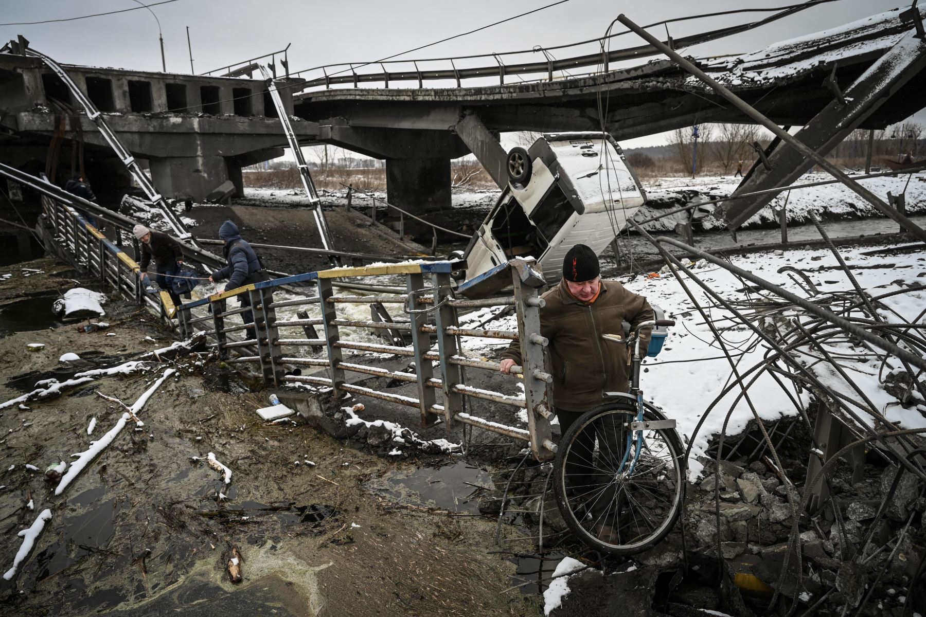 Los civiles cruzan un río en un puente volado en el frente norte de Kiev. Foto: AFP
