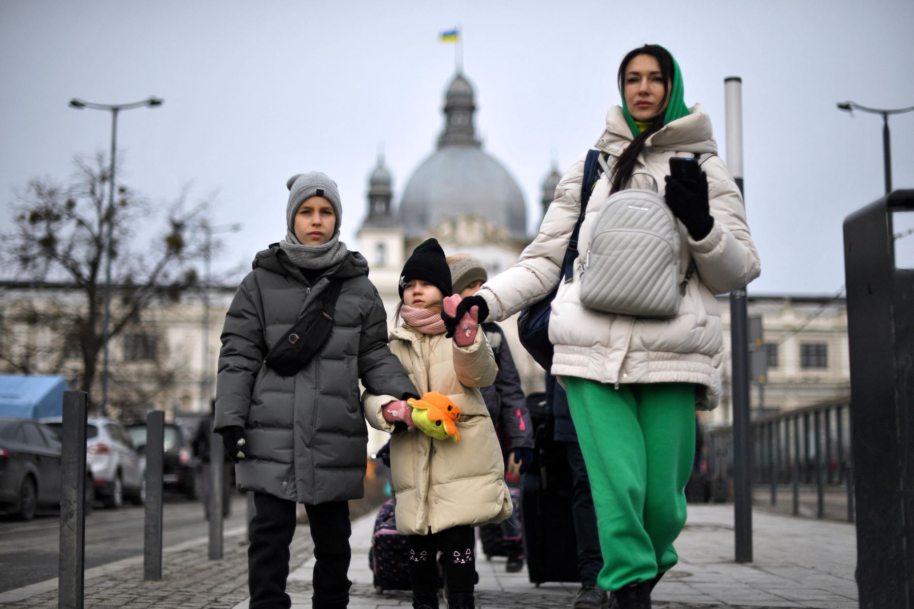 Una mujer con niños camina frente a la estación de tren en Ucrania. Foto: AFP