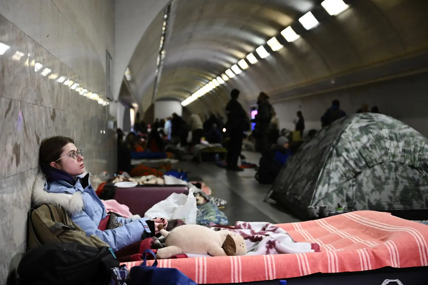 Una mujer joven se sienta en una estación de metro subterránea utilizada como refugio antibombas en Kiev. En el séptimo día de combates en Ucrania, Rusia reclama el control  de la ciudad portuaria sureña de Kherson.
Foto: AFP